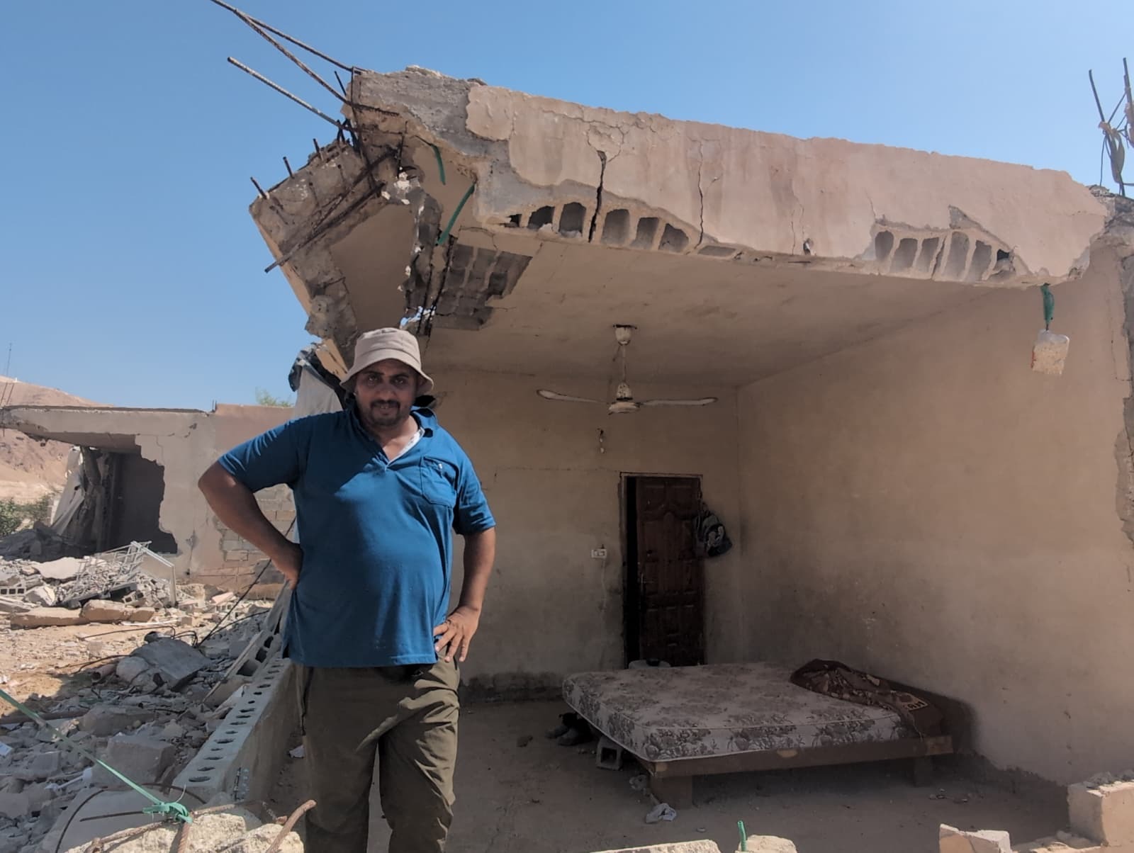 Ali Kaabneh in front of his partially destroyed home he still lives in [Courtesy of Unarmed Civilian Protection in Palestine]