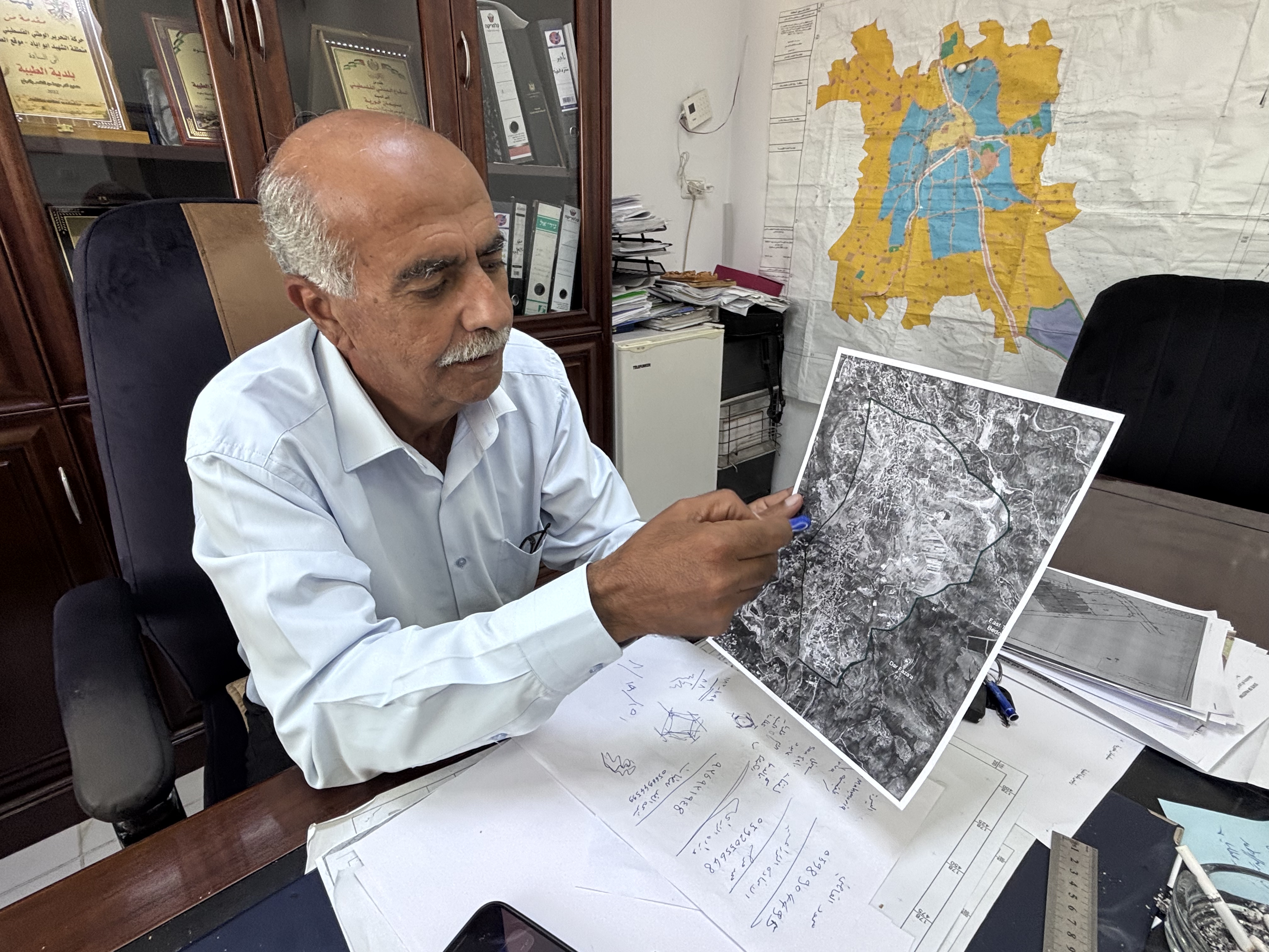 Mayor Suleiman Khourieh looking at a map of the closed military zone around Taybeh [Al Jazeera]