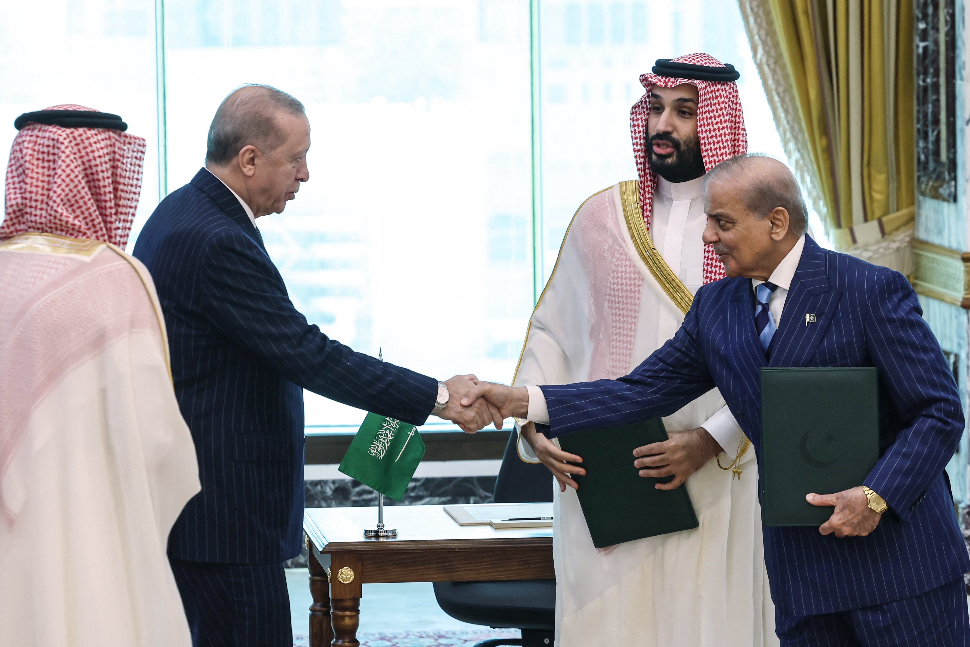 This handout photograph taken and released by the Turkish Presidency press office on August 7, 2026, shows Turkey's President Recep Tayyip Erdogan (L) shaking hands with Pakistan’s Prime Minister Shehbaz Sharif as Saudi Arabia's Crown Prince Mohammed bin Salman (2nd R) looks on after signing a joint defence agreement in Mecca.