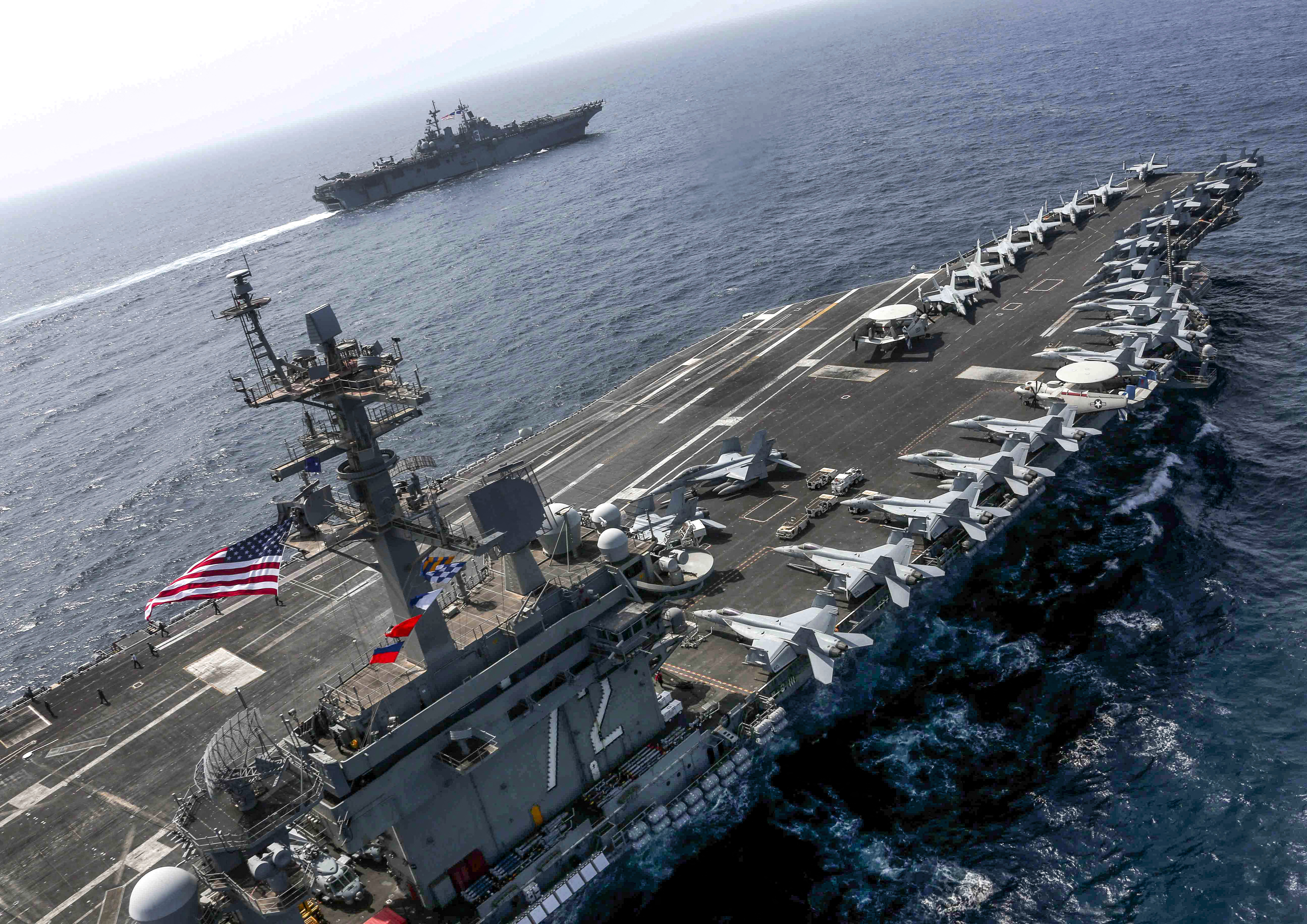(FILES) This handout picture released by the US Navy on May 17, 2019 shows the Nimitz-class aircraft carrier USS Abraham Lincoln (CVN 72) and the Wasp-class Amphibious Assault Ship USS Kearsarge (LHD 3) conducting joint operations in the U.S. 5th Fleet area of operations in the Arabian Sea.