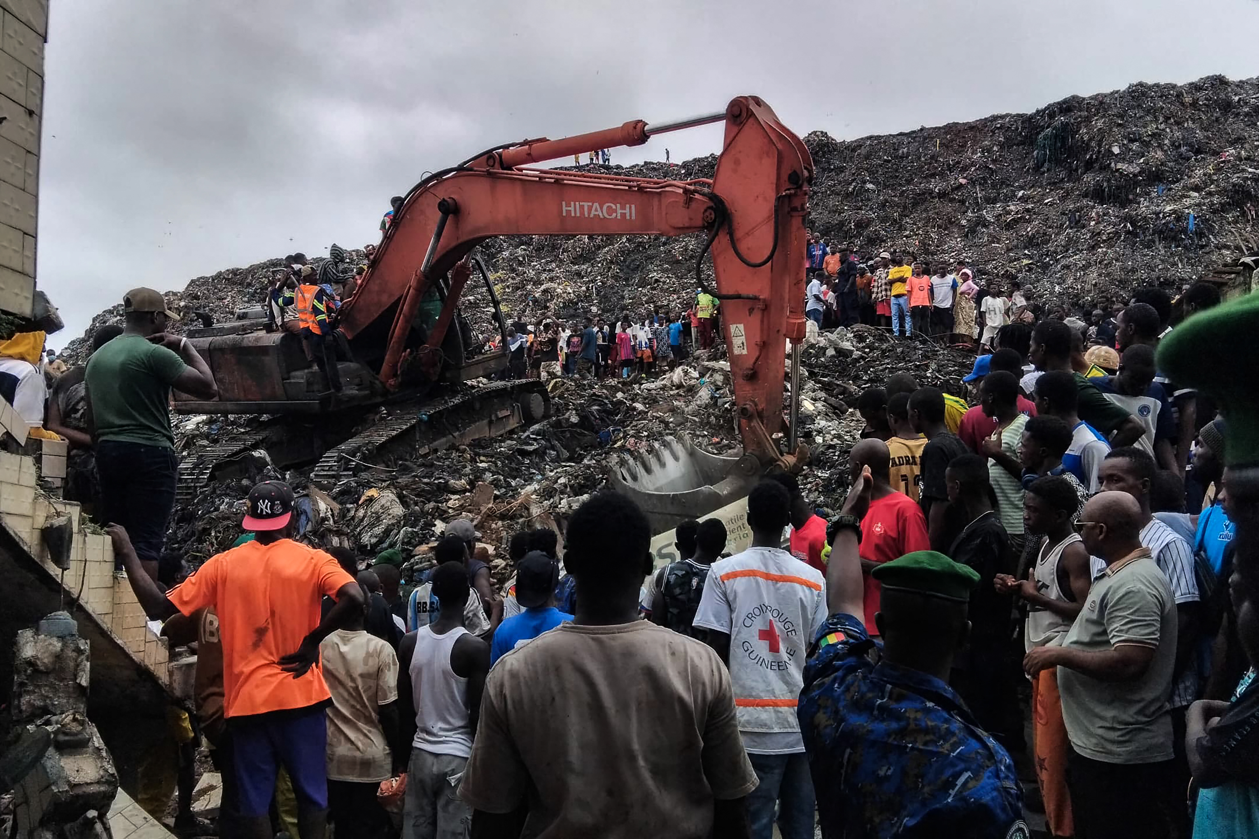 TOPSHOT - Residents and rescuers use an excavator to search for bodies after a landslide struck the Dar es Salaam dumpsite overnight in Conakry on August 23, 2026.