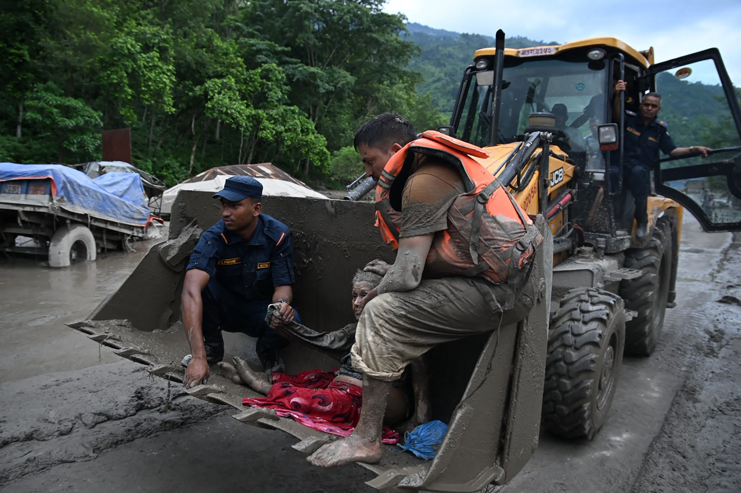 Rescue personnel use an excavator to carry a person affected by flash floods at Devghat in Nepal's Nuwakot district on August 26, 2026.