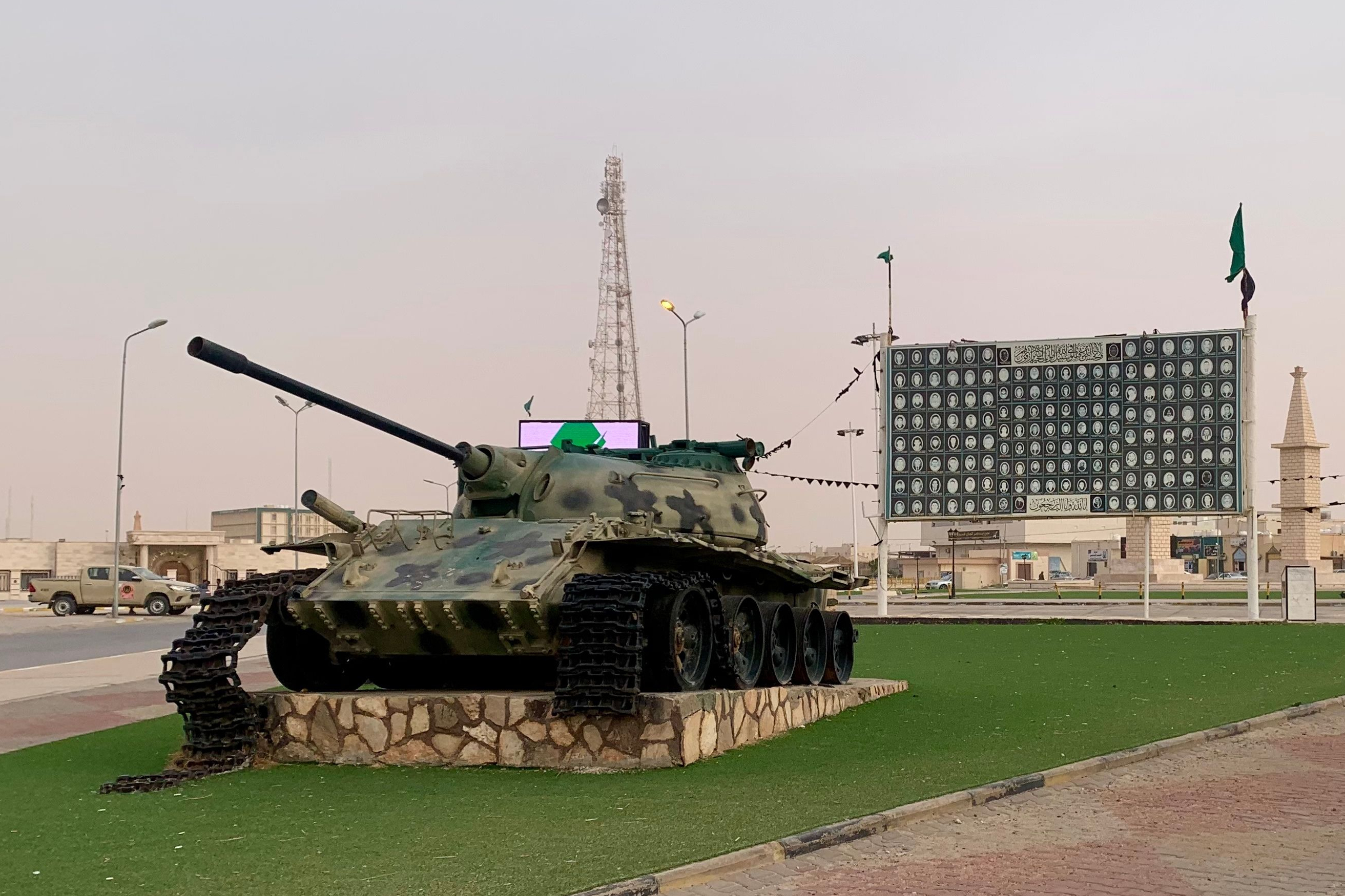 A destroyed tank is seen in front of a banner showing some of the victims of the Libyan revolution at Bani Walid city, where the body of Seif al-Islam, son of then Libyan Leader Moammar Gadhafi, is expected to be buried, Wednesday, Feb. 4, 2026. (AP Photo/Yousef Murad)