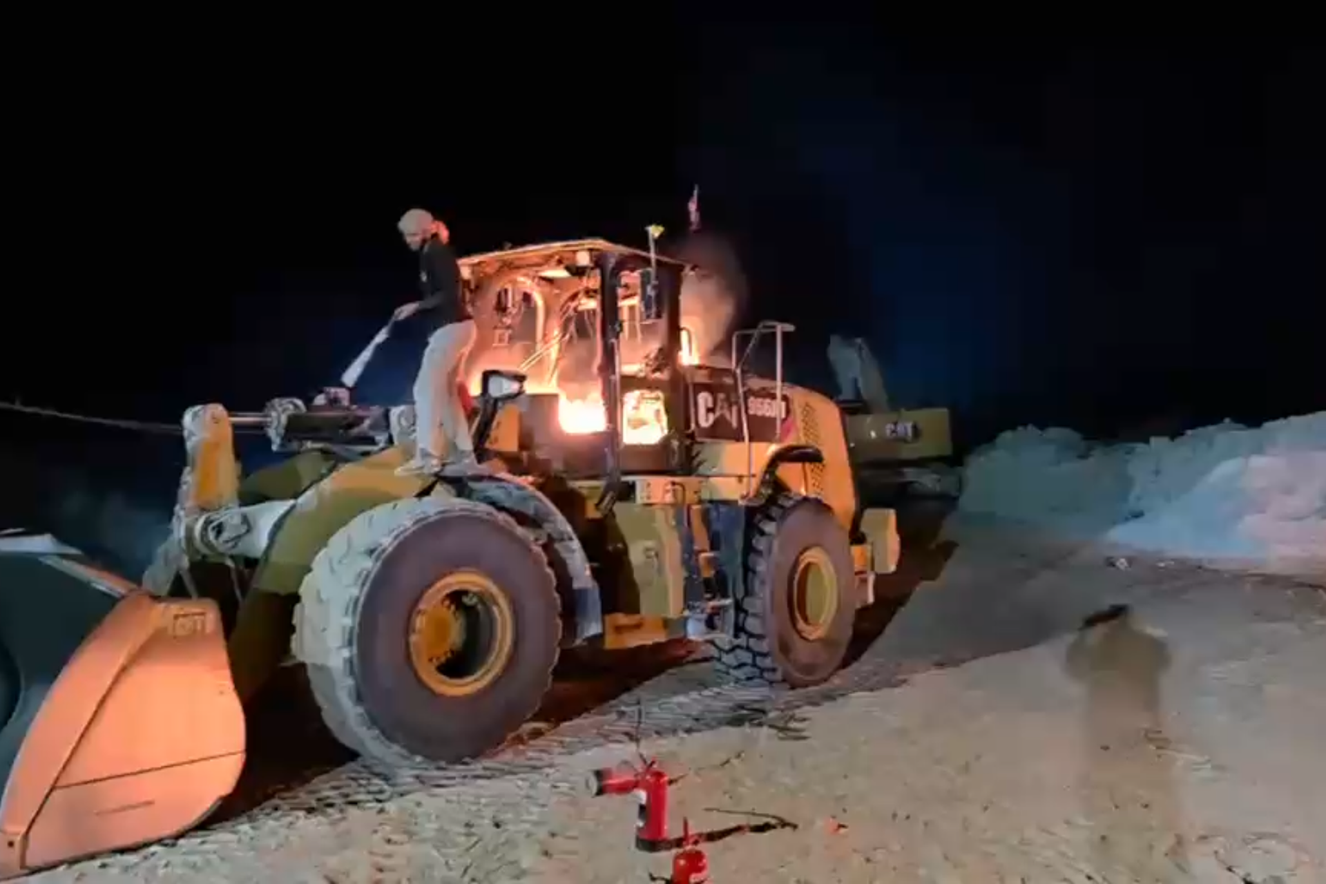 A bulldozer at the Ein Samia stone crusher shows severe damage after Israeli settlers infiltrated the site and set fire to heavy equipment [Screengrab/Al Jazeera]