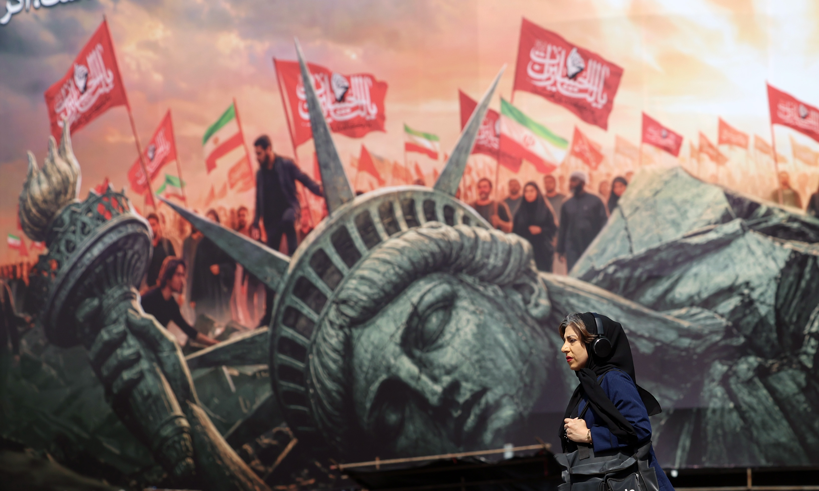 epaselect epa13165938 An Iranian woman walks next to an anti-US billboard at the Enghelab square in central Tehran, Iran, 13 August 2026. Tensions between Iran and the US remain high as opposing claims persist over shipping control in the Strait of Hormuz. EPA/ABEDIN TAHERKENAREH RESTRICTIONS: NO Access Israel Media/Persian Language TV Stations Outside Iran/Strictly No Access BBC Persian/VOA Persian/Manoto TV/Iran International TV. (As mandated by Iran's Directorate General for Foreign Media) --