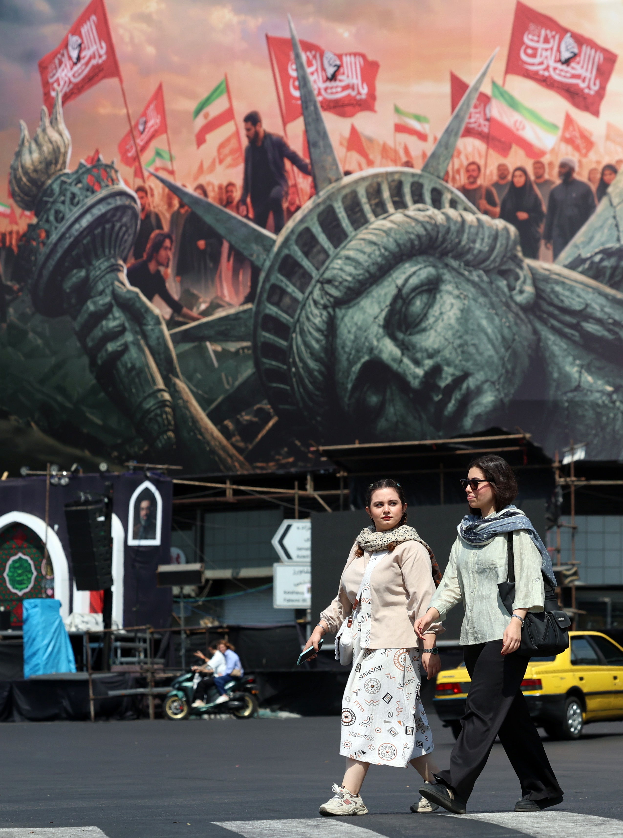 epa13165937 Iranian women walk next to an anti-US billboard at the Enghelab square in central Tehran, Iran, 13 August 2026. Tensions between Iran and the US remain high as opposing claims persist over shipping control in the Strait of Hormuz. EPA/ABEDIN TAHERKENAREH RESTRICTIONS: NO Access Israel Media/Persian Language TV Stations Outside Iran/Strictly No Access BBC Persian/VOA Persian/Manoto TV/Iran International TV. (As mandated by Iran's Directorate General for Foreign Media) --