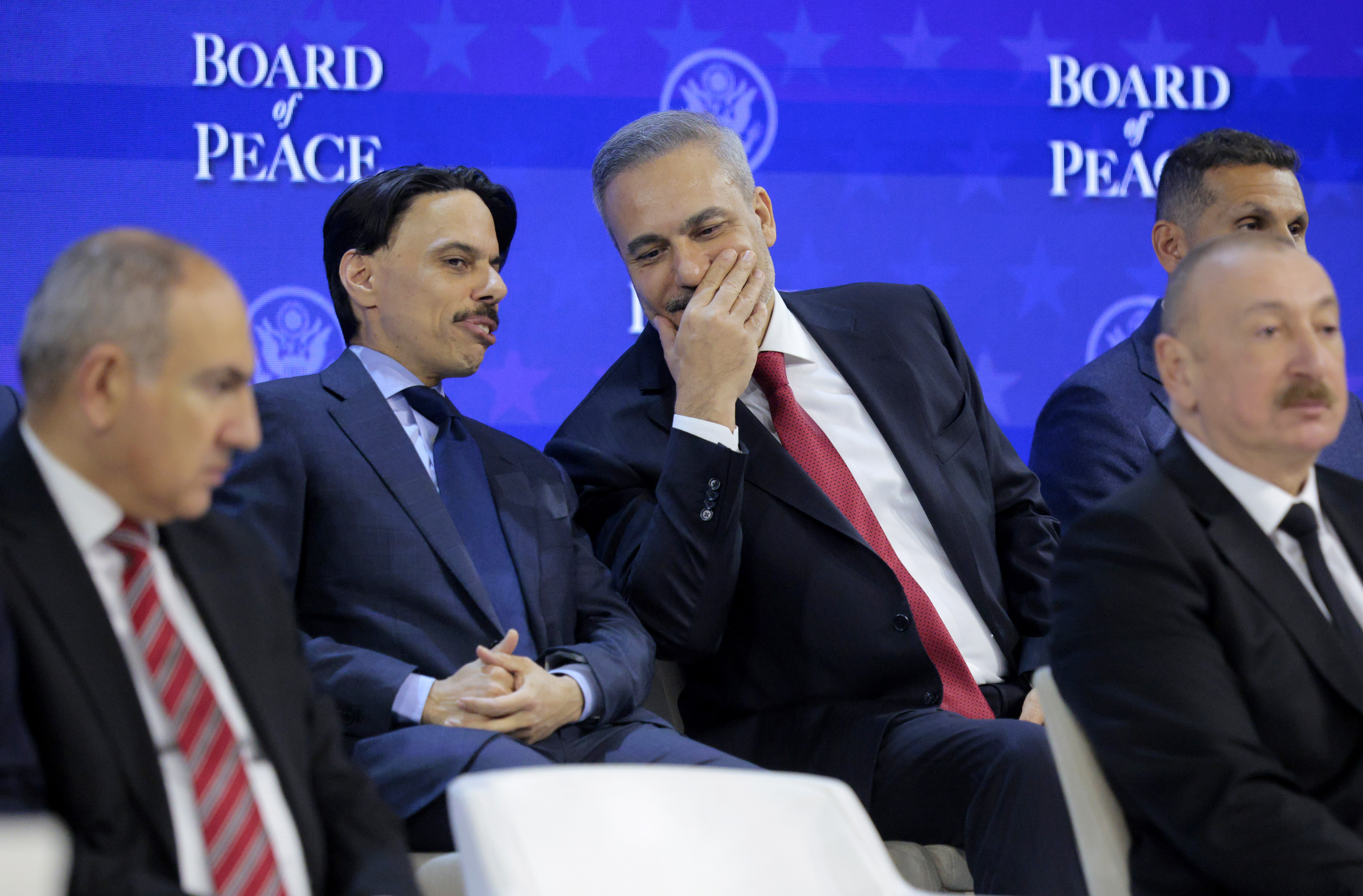 DAVOS, SWITZERLAND - JANUARY 22: Saudi Arabia's Foreign Minister Faisal bin Farhan (L) speaks with Turkey's Foreign Minister Hakan Fidan as U.S. President Donald Trump presents the “Board of Peace” at the World Economic Forum (WEF) on January 22, 2026 in Davos, Switzerland. The US-backed “Board of Peace” is intended to administer the fragile ceasefire in the Gaza Strip after the war between Israel and Hamas. The final makeup of the board has not been confirmed. (Photo by Chip Somodevilla/Getty Images)