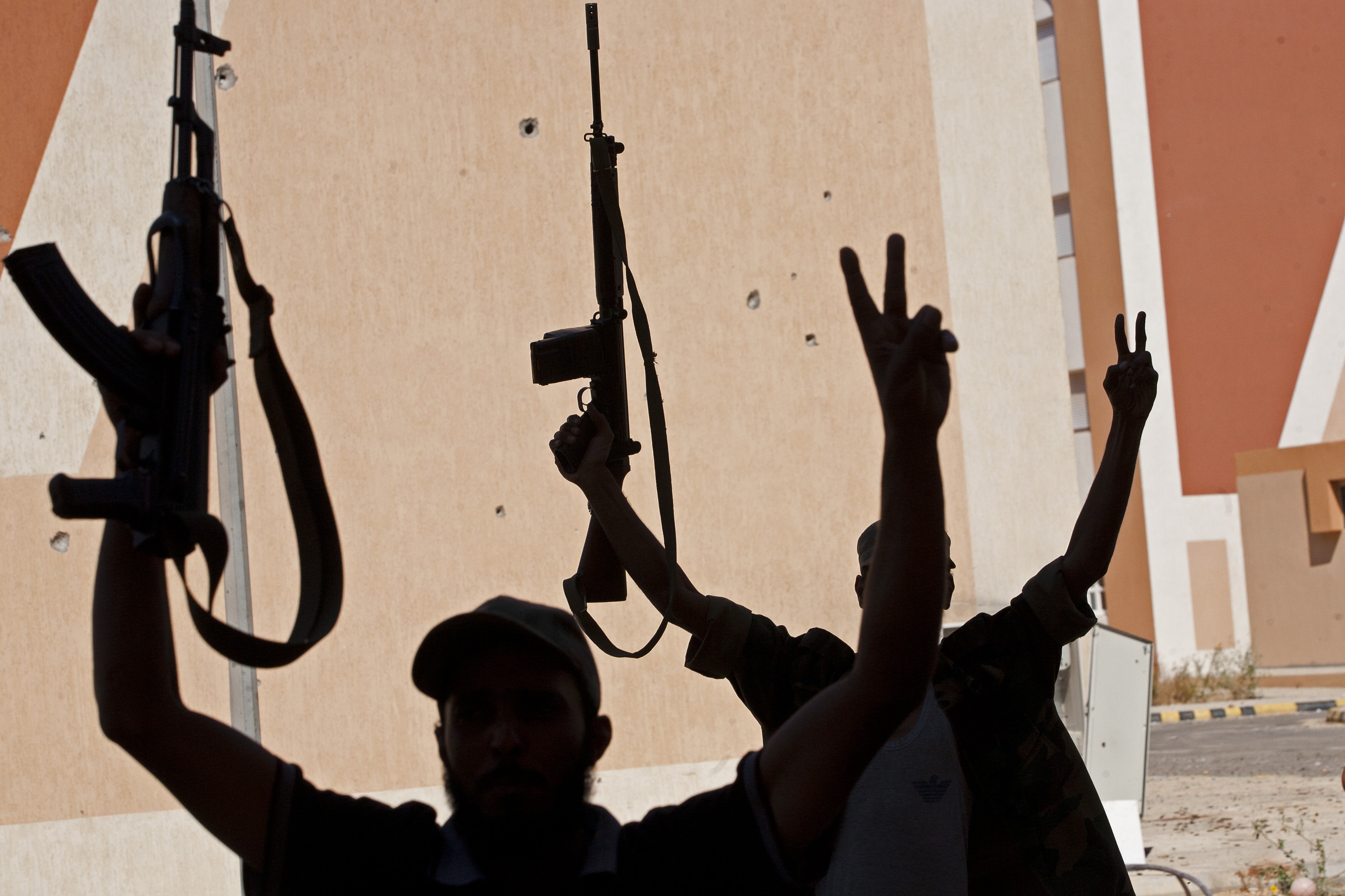 SIRTE, LIBYA - OCTOBER 8: National Transitional Council (NTC) fighter celebrate during street battle in the 700 complex area of "Emarat" against Muammar Gaddafi's troops on October 8, 2011 in Sirte, Libya. NTC fighters say this is the final assault on Muammar Gaddafi's home town as they capture the main hospital, University and the Ouagadougou conference centre in the city. (Photo by Majid Saeedi/Getty Images)
