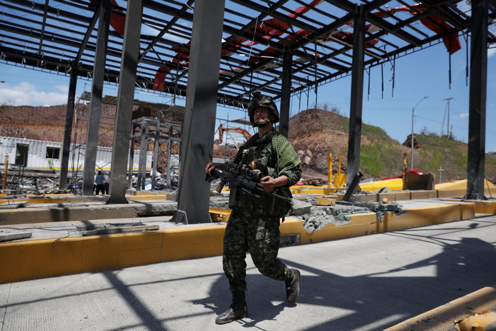 A soldier walks through a toll plaza along the Pan-American Highway damaged in a car bomb explosion that the army blamed on FARC dissident groups in Santander de Quilichao, Colombia, Saturday, Aug. 8, 2026. (AP Photo/Santiago Saldarriaga)