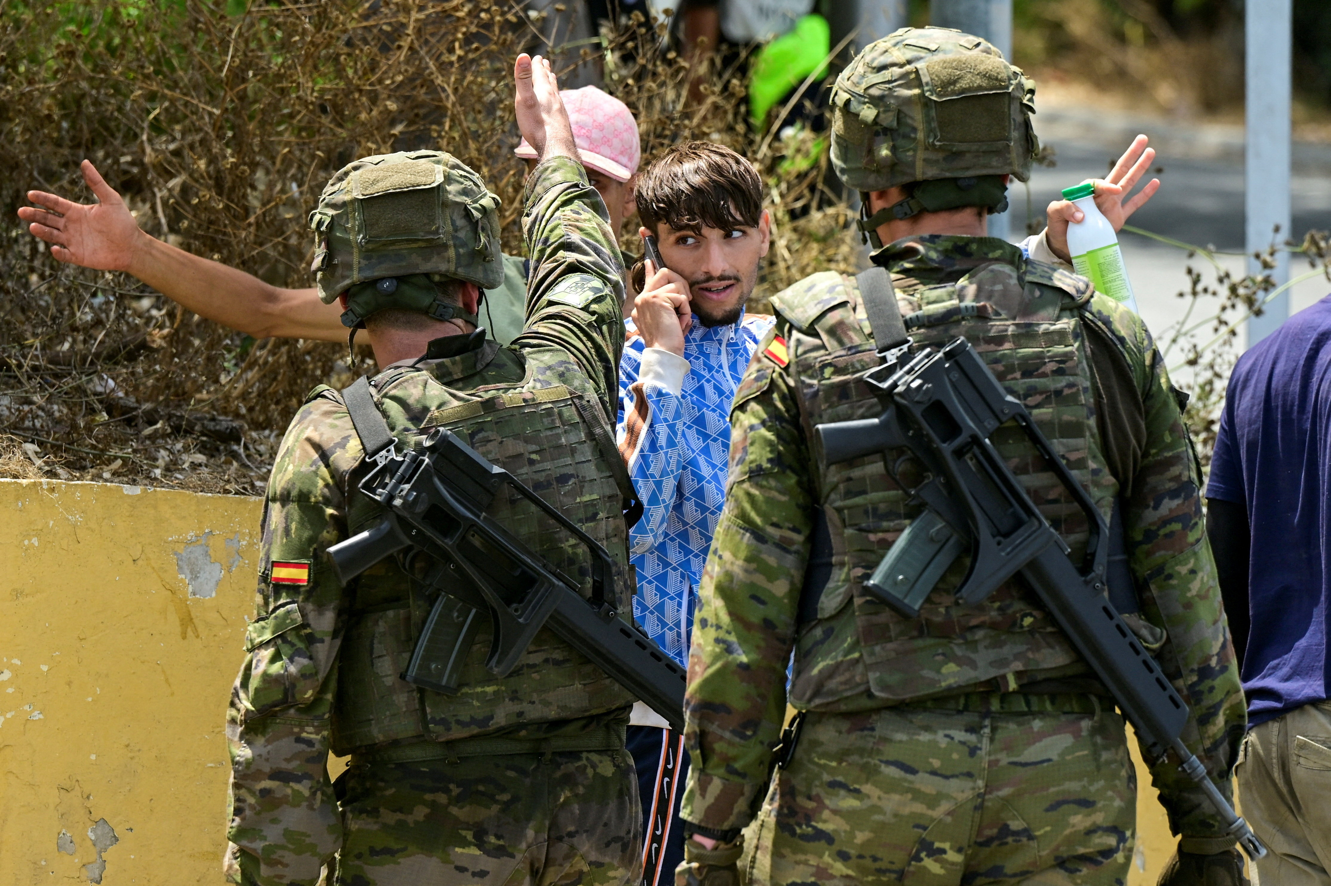 Spanish soldiers gesture towards migrants, as they question them, following mass crossings of migrants on foot and by sea from Morocco into Spanish territory, in Ceuta, Spain, August 1, 2026. REUTERS/Fabian Bimmer TPX IMAGES OF THE DAY
