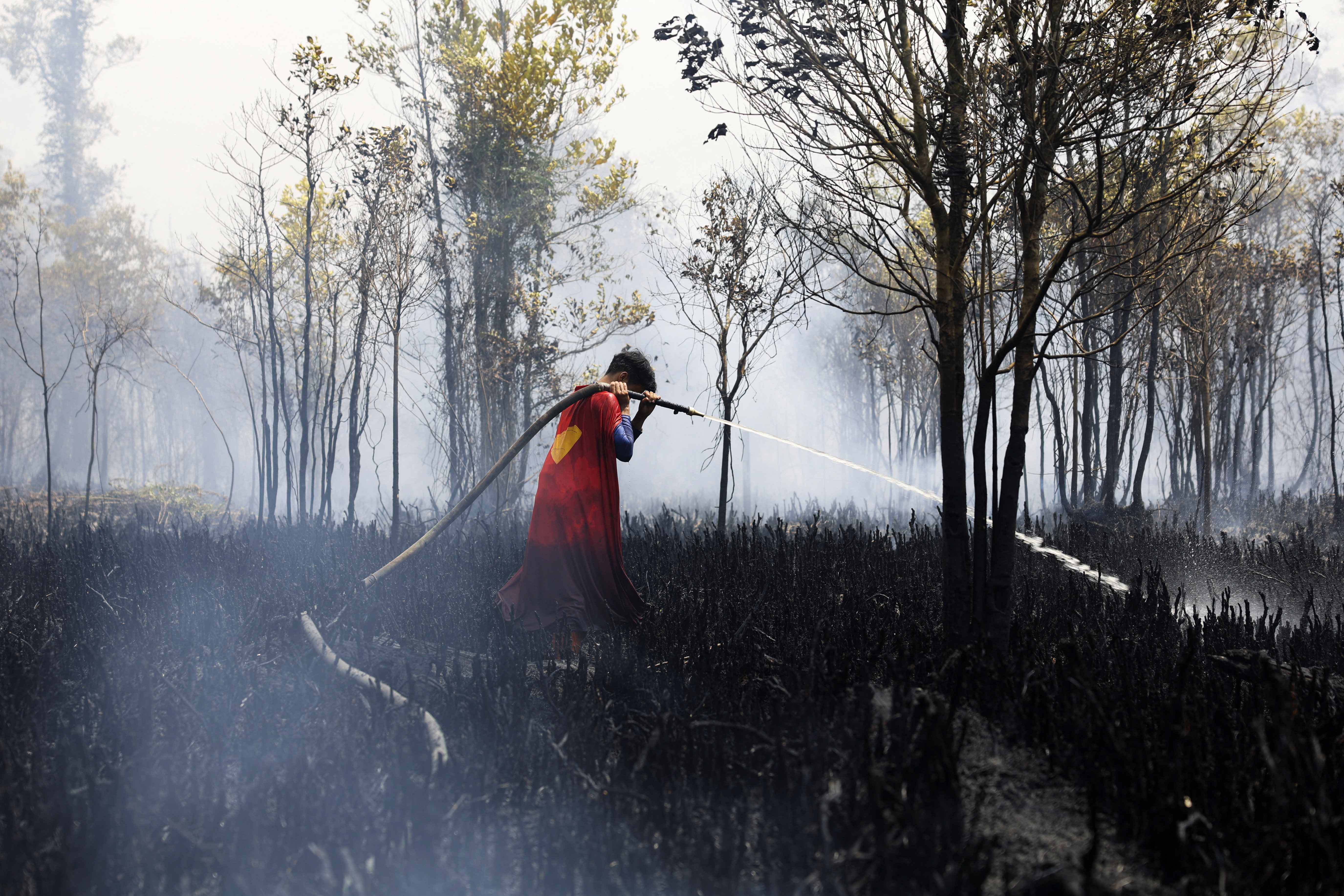 Rudiyansah, 16, wears a Superman costume while extinguishing a fire at a wildfire-affected area in Palangka Raya, Central Kalimantan province, Indonesia, August 14, 2026. REUTERS/Ajeng Dinar Ulfiana TPX IMAGES OF THE DAY
