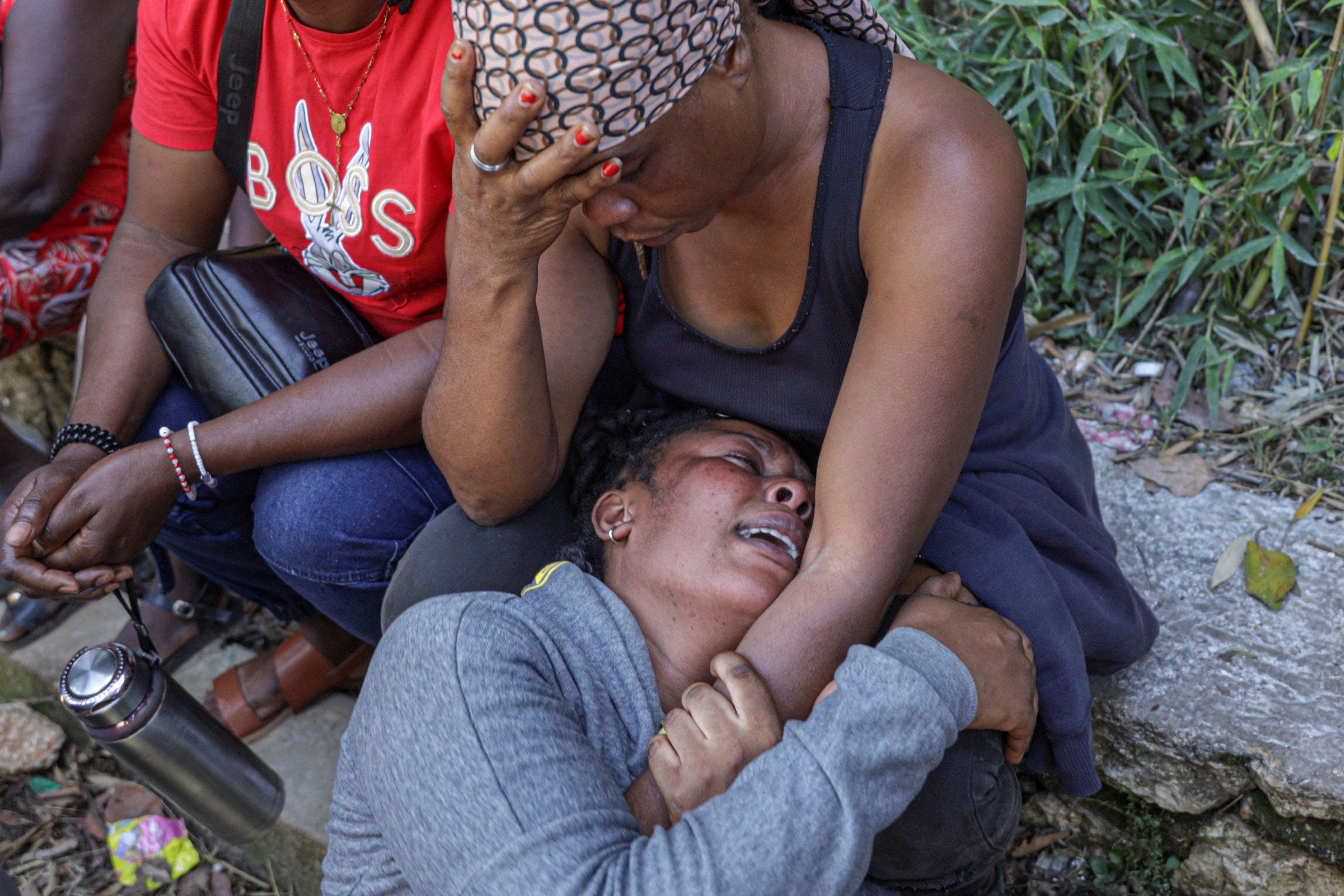 Women mourn near the bodies of people killed during an overnight raid by an armed gang, on the outskirts of Port-au-Prince, in Kenscoff, Haiti, August 24, 2026. REUTERS/Patrice Noel