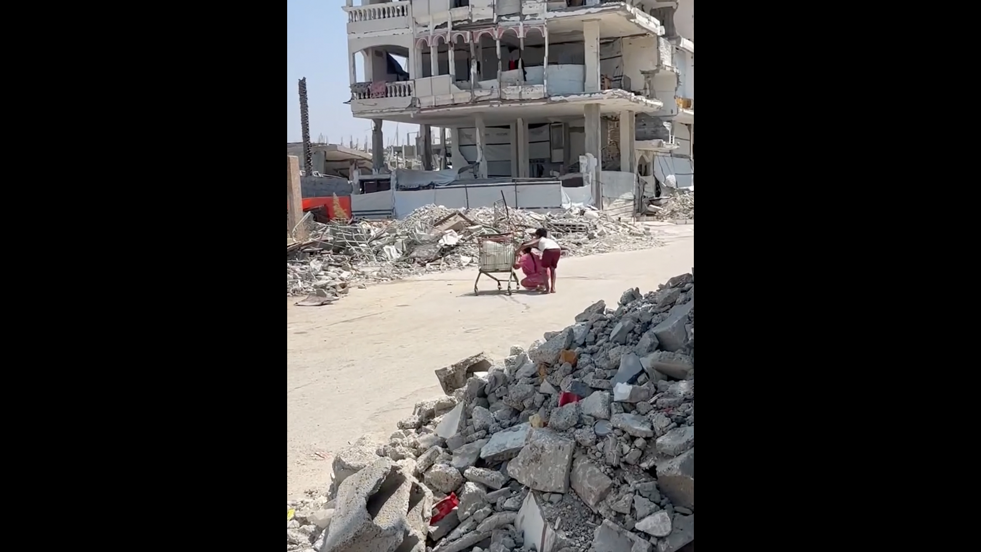 Children take cover behind shopping cart during Israeli drone fire