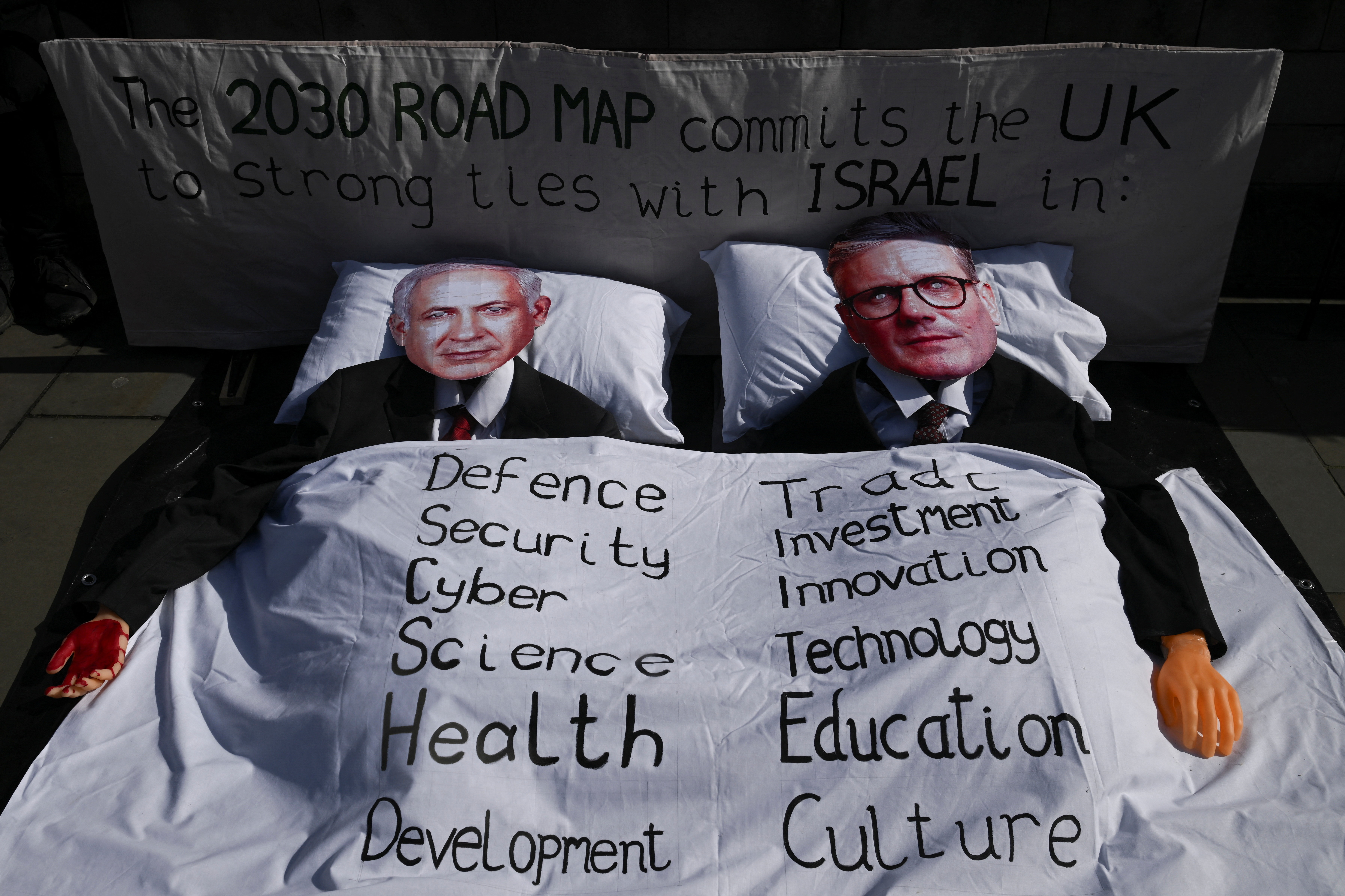 A banner and cutout photographs depicting faces of Israel's Prime Minister Benjamin Netanyahu and British Prime Minister Keir Starmer in bed together, that reads "To the 2030 UK-Israel Road Map-A Partnership in Genocide, End the UK's Love affair with Israel" at Parliament Square in London, Britain, March 11, 2026. REUTERS/Jaimi Joy