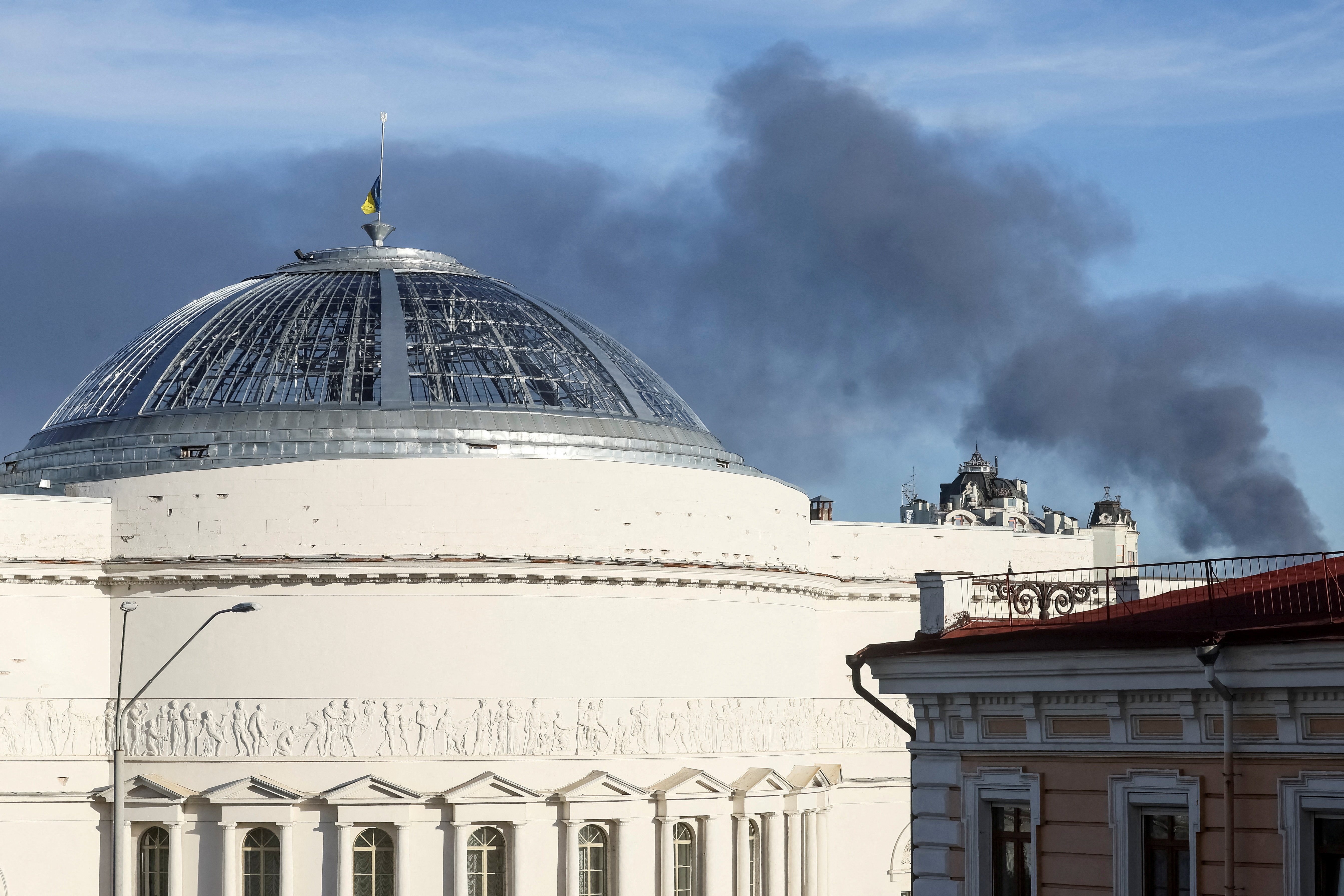 The flag flies on a roof as smoke rises in the city during a Russian drone strike, amid Russia's attack on Ukraine, in Kyiv, Ukraine September 8, 2026. REUTERS/Gleb Garanich TPX IMAGES OF THE DAY