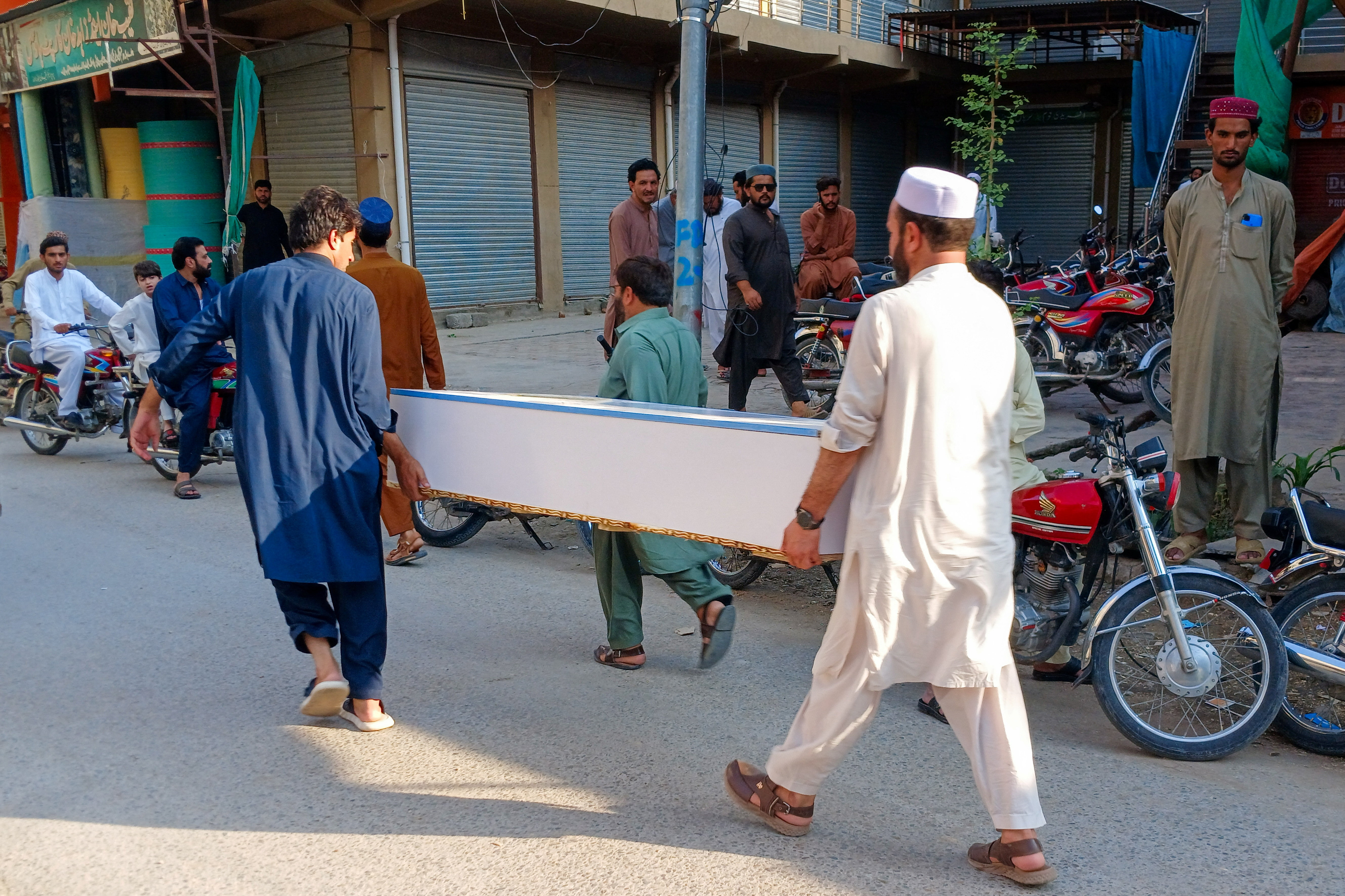 People carry an empty coffin box along a street leading to a police facility following a suicide attack at the facility in Kohat, Pakistan, September 18, 2026. REUTERS/Stringer