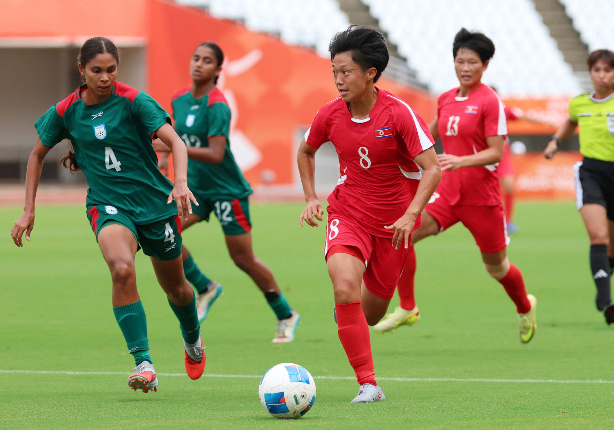 North Korea's Ri Song-a (C) runs with the ball during the 2026 Asian Games women's group B football match against Bangladesh at Yanmar Stadium Nagai in Osaka on September 14, 2026. North Korea's formidable women's football team launched their Asian Games with a 10-0 hammering of Bangladesh, cheered on by several hundred pro-Pyongyang fans in Osaka. (Photo by JIJI Press / AFP) / Japan OUT