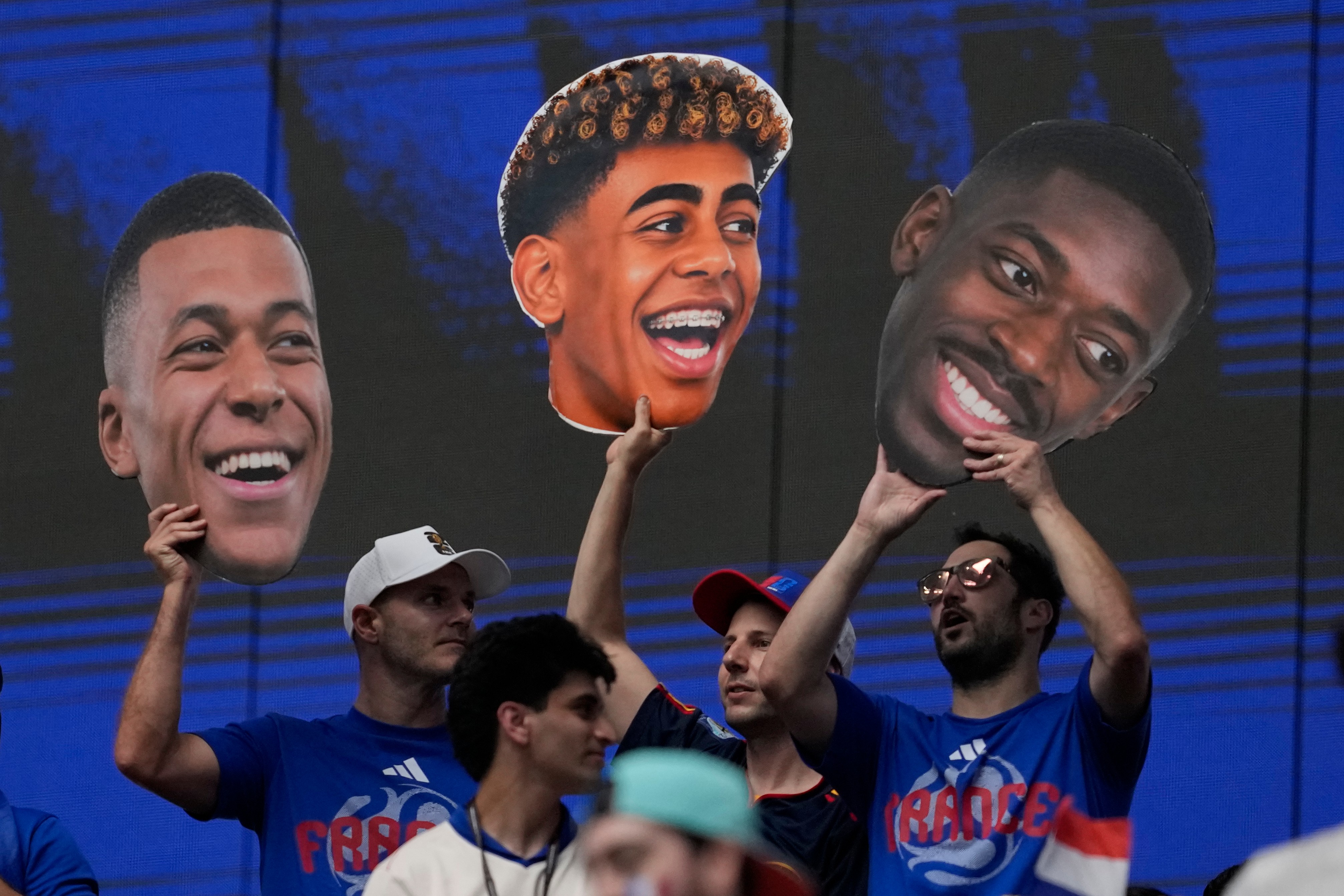 France fans hold pictures of France's Kylian Mbappe (10), left, Spain's Lamine Yamal (19), center, and France's Ousmane Dembele (7) before the World Cup semifinal