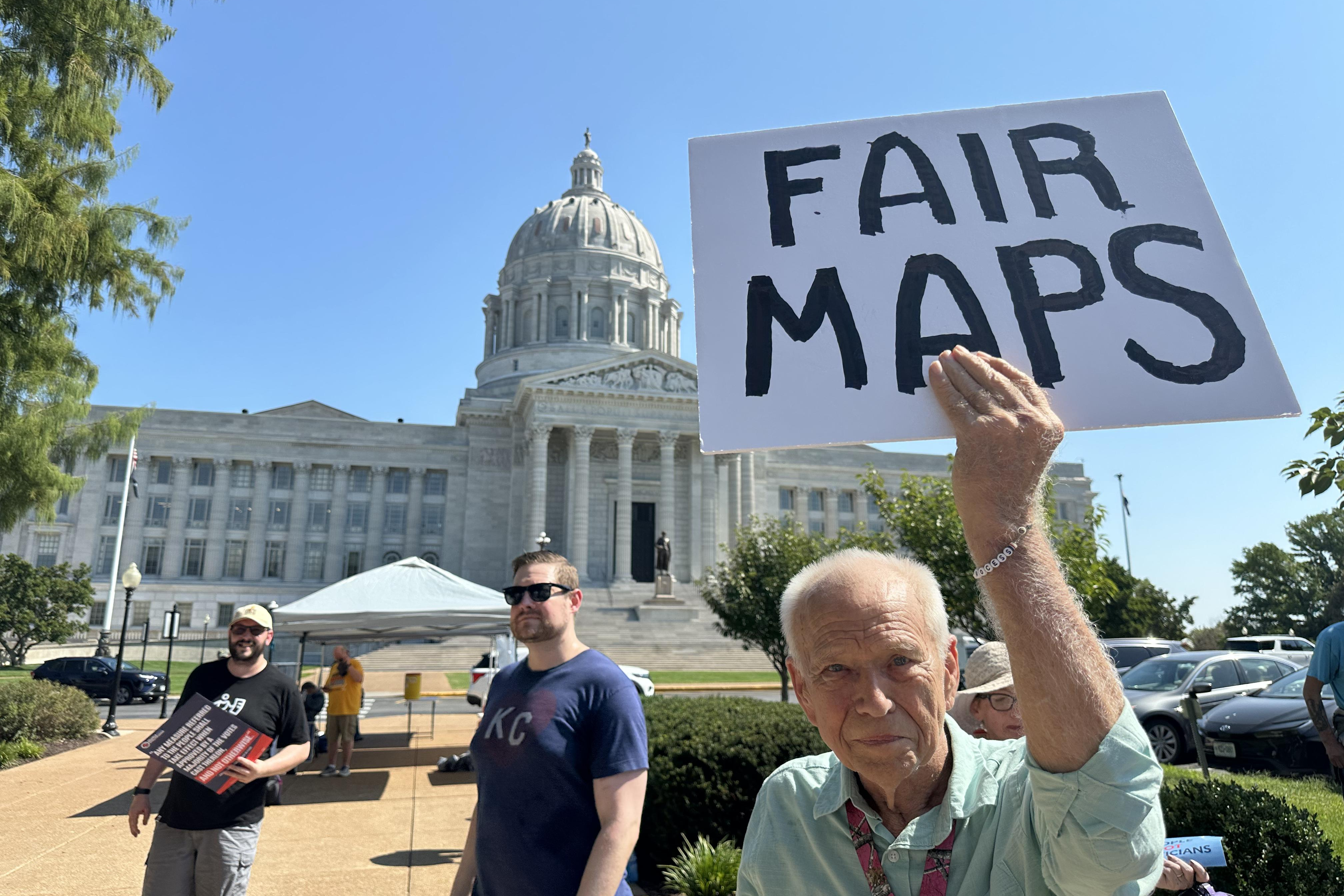 This photo taken with a smartphone shows Steve Perry, of Kansas City, holding a sign in opposition to Missouri’s congressional redistricting plan on Wednesday, Sept. 2, 2026, outside the state Capitol, in Jefferson City, Mo. (AP Photo/David A. Lieb)