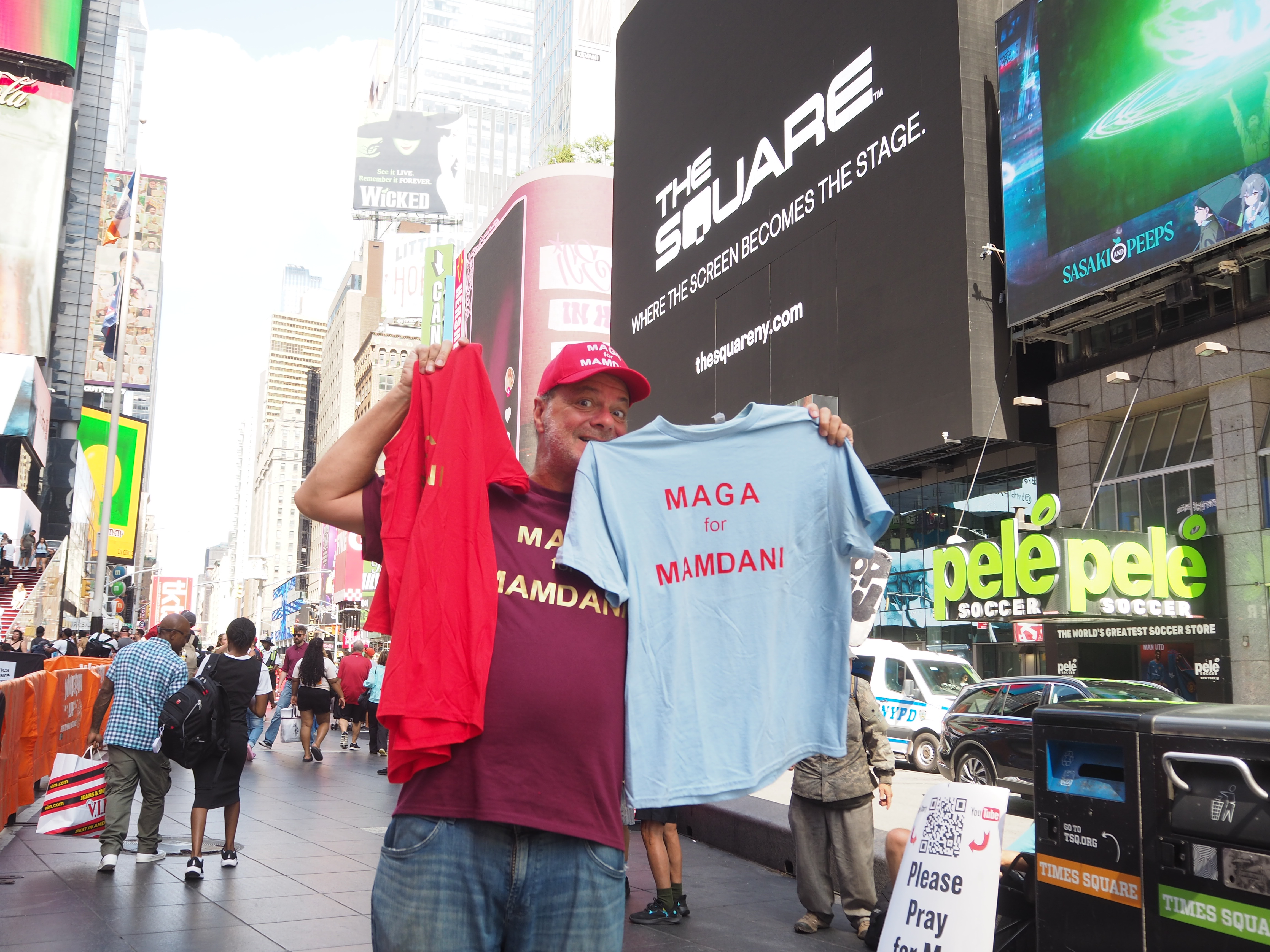 Ron Barba holds up a shirt that says "MAGA for Mamdani," holding one side with his teeth.