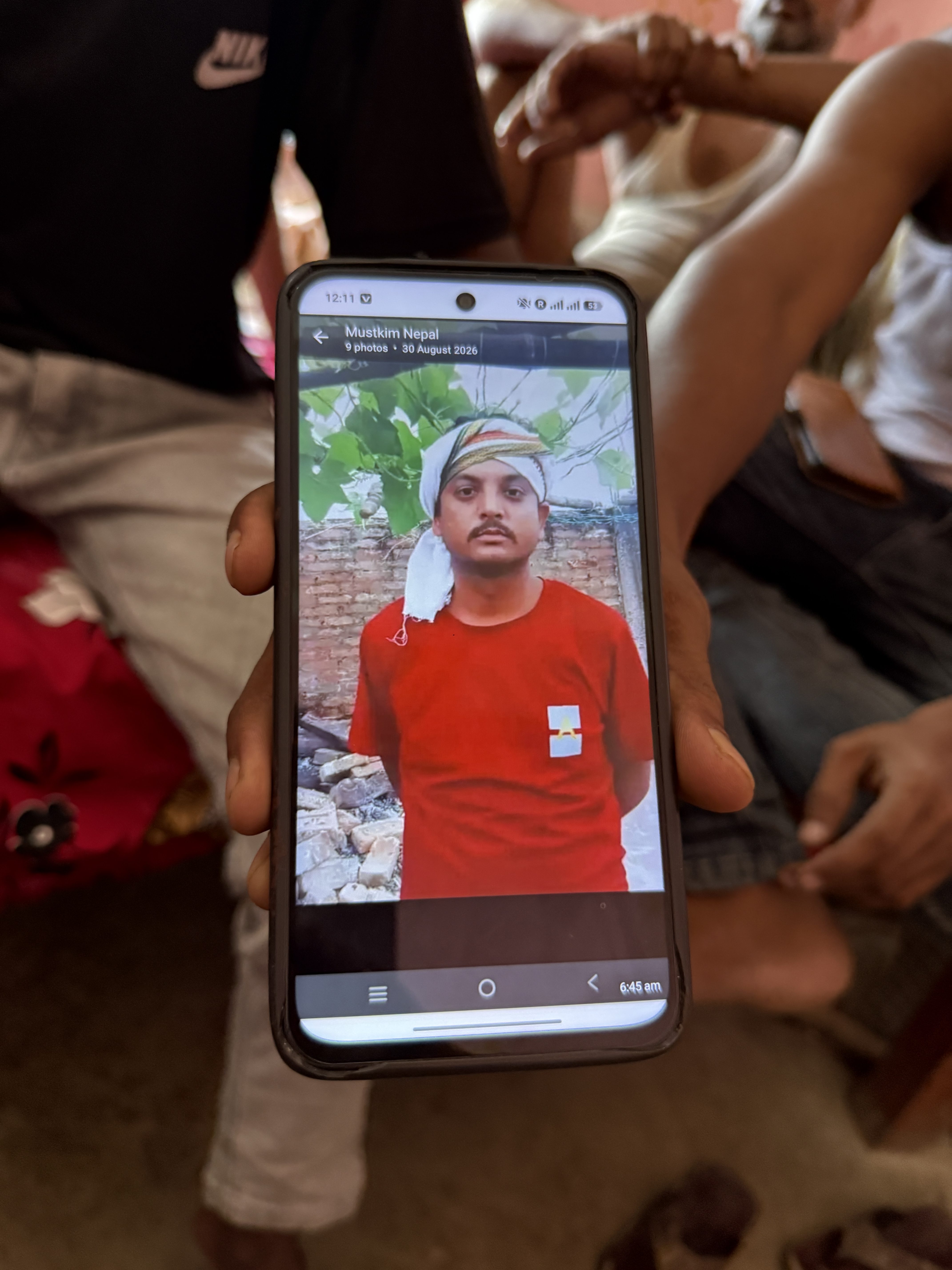 A hand holds a mobile phone with a man's picture visible on it.