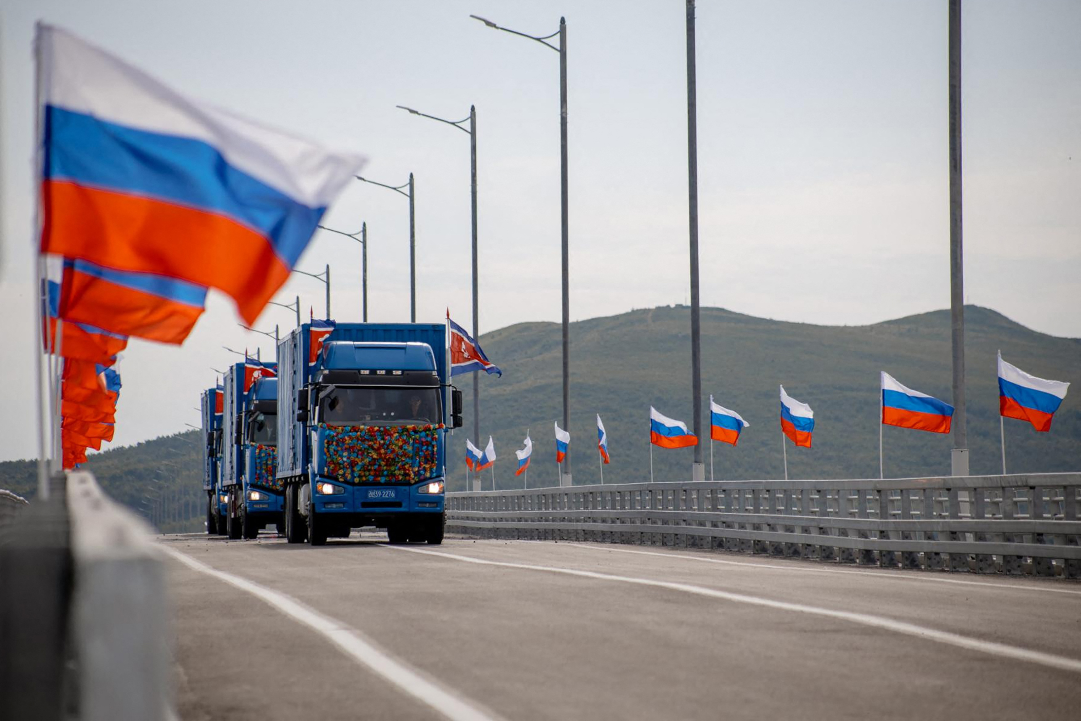 In this handout image released by the Russian Transport Ministry on September 7, 2026, national flags of Russia wave in the wind and North Korean trucks cross the new Russia-North Korea road bridge over the Tumen River, during the opening ceremony. (Photo by Handout / Russian Transport Ministry / AFP) / RESTRICTED TO EDITORIAL USE - MANDATORY CREDIT "AFP PHOTO / RUSSIAN TRANSPORT MINISTRY" - HANDOUT - NO MARKETING NO ADVERTISING CAMPAIGNS - DISTRIBUTED AS A SERVICE TO CLIENTS