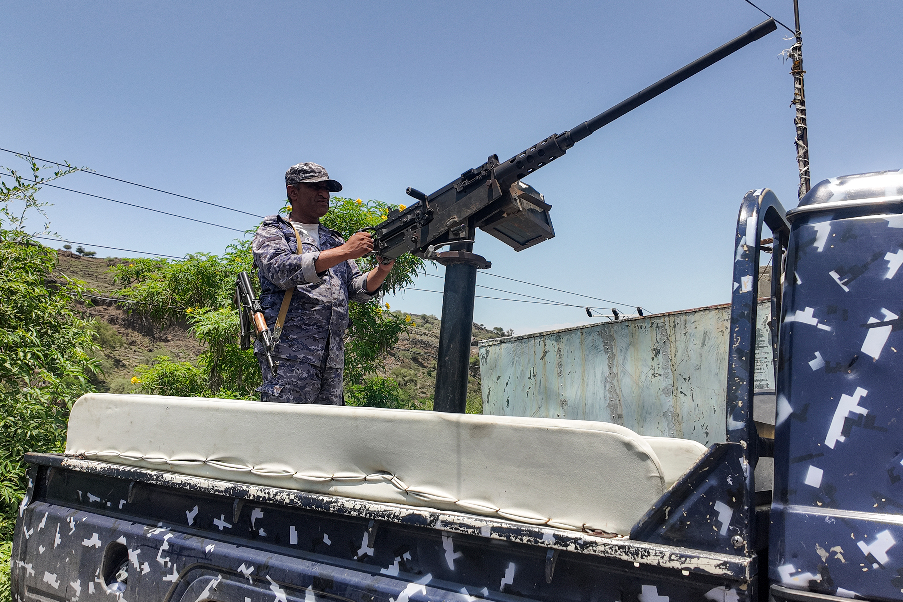 An armed personnel mans a turret mounted on the back of a pick-up truck.