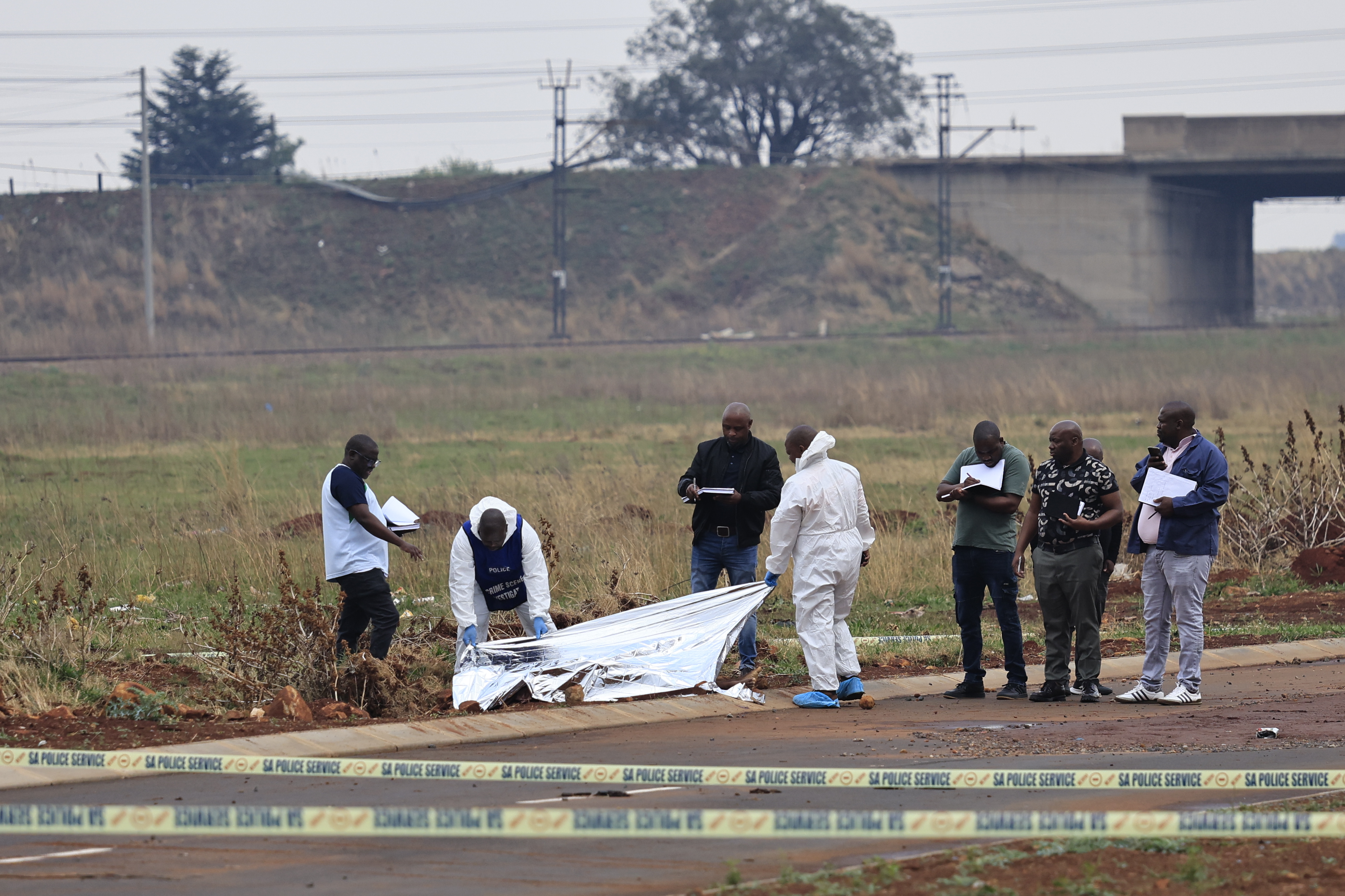 epaselect epa13245358 Members of the SAPS (South African Police Service) and state pathologists inspect the body of one of the women found dumped on the side of a road in Boksburg, Johannesburg, South Africa, 17 September 2026. The remains of nine murdered women have been found in recent weeks as SAPS tries to arrest the killer. EPA/Kim Ludbrook
