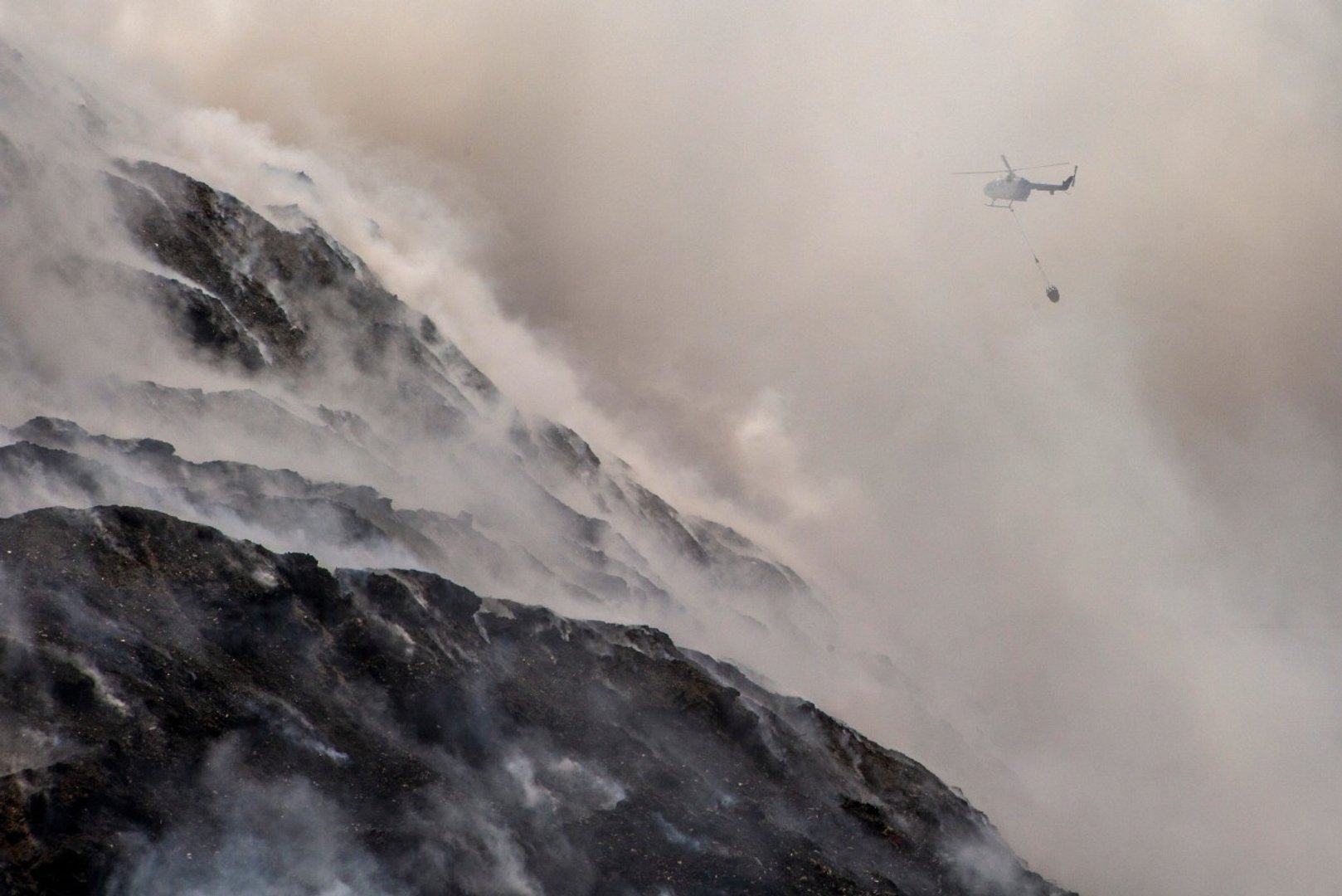 A helicopter conducts water bombing to extinguish a fire at the Putri Cempo landfill in Solo, Central Java, on September 4, 2026. [Photo by DEVI RAHMAN / AFP]