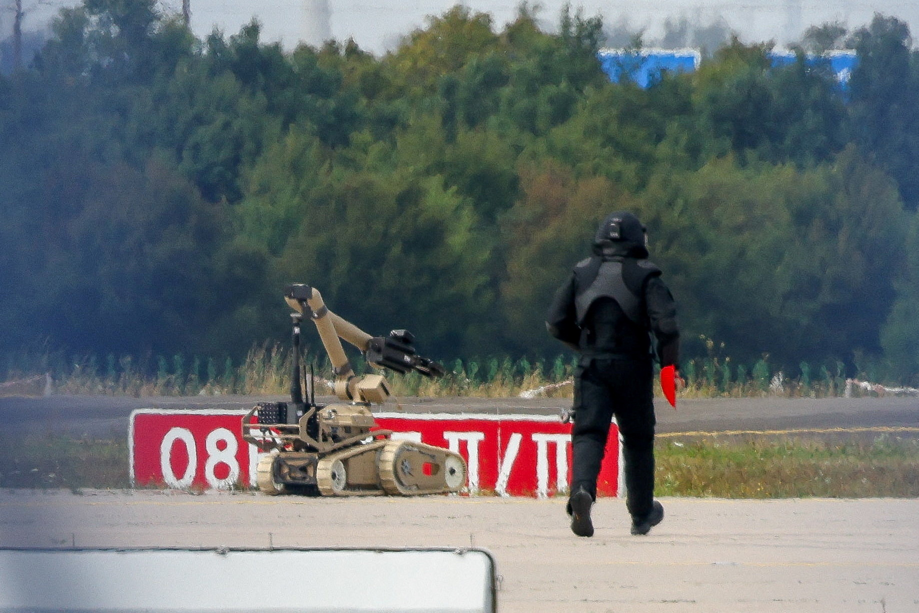 FILE PHOTO: A police officer in protective clothing walks next to an explosive-disarming robot (EOD) at Leipzig/Halle Airport in Schkeuditz, Germany, August 5, 2026, after the police said explosives experts examined a drone found near a runway, and after a DHL cargo aircraft hit an unknown object as it was climbing away from the airport overnight, prompting an unscheduled landing in Hanover, according to a source familiar with the incident. REUTERS/Axel Schmidt/File Photo