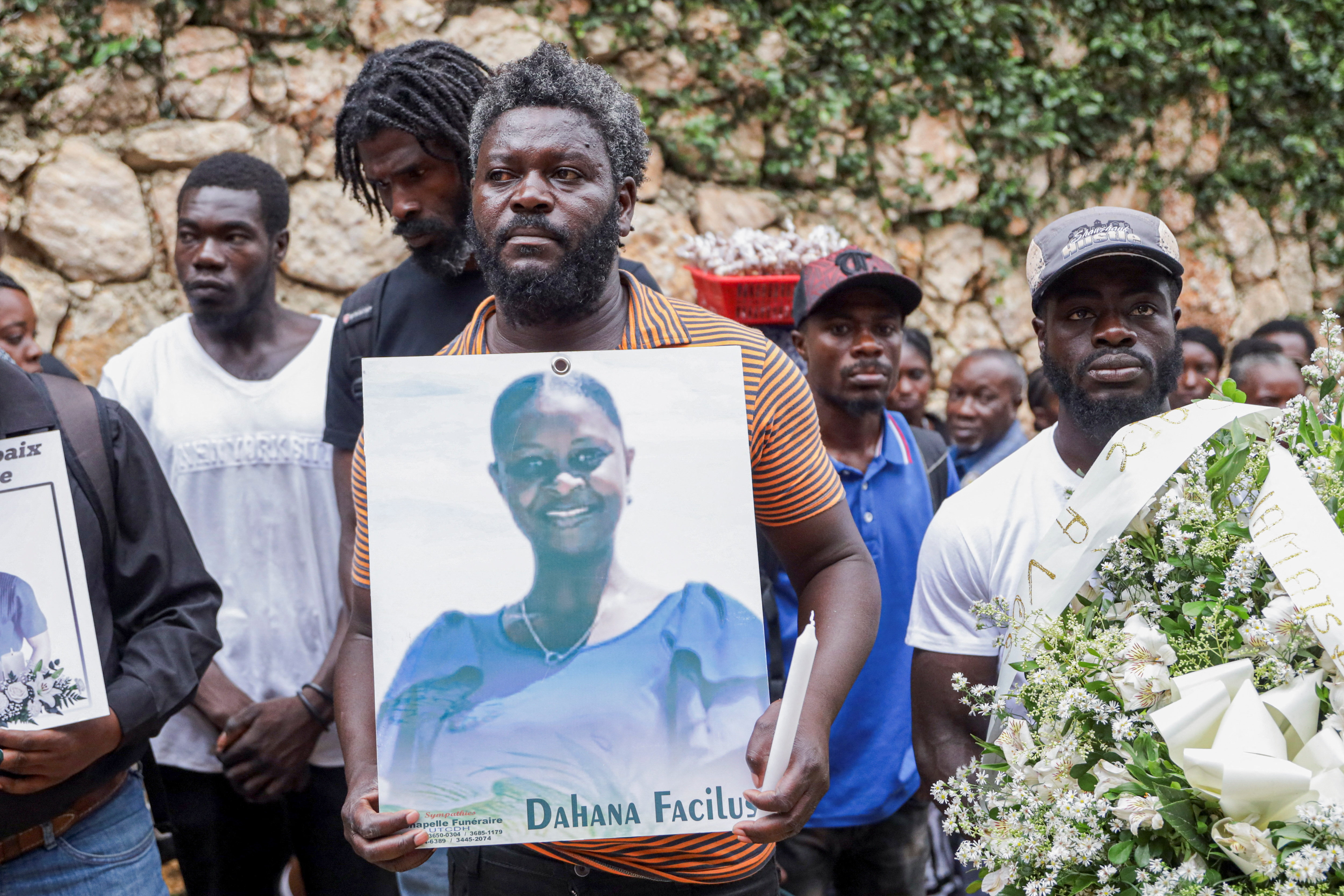 A mourner at a funeral service holds a picture of a person killed in an armed gang attack on August 23, in Kenscoff, Haiti, September 2, 2026. REUTERS/Patrice Noel