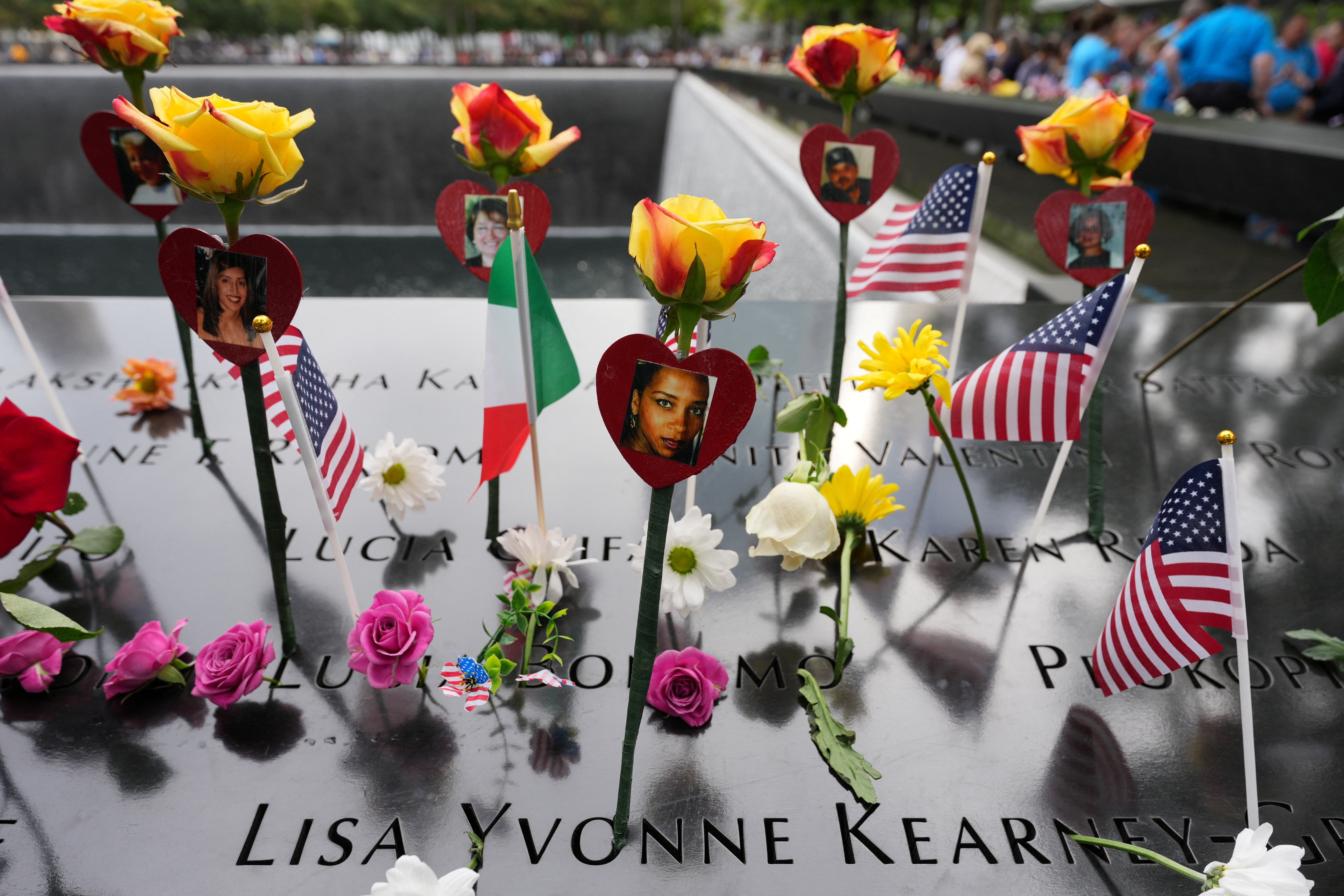 Flowers adorn a reflecting pool during a memorial.