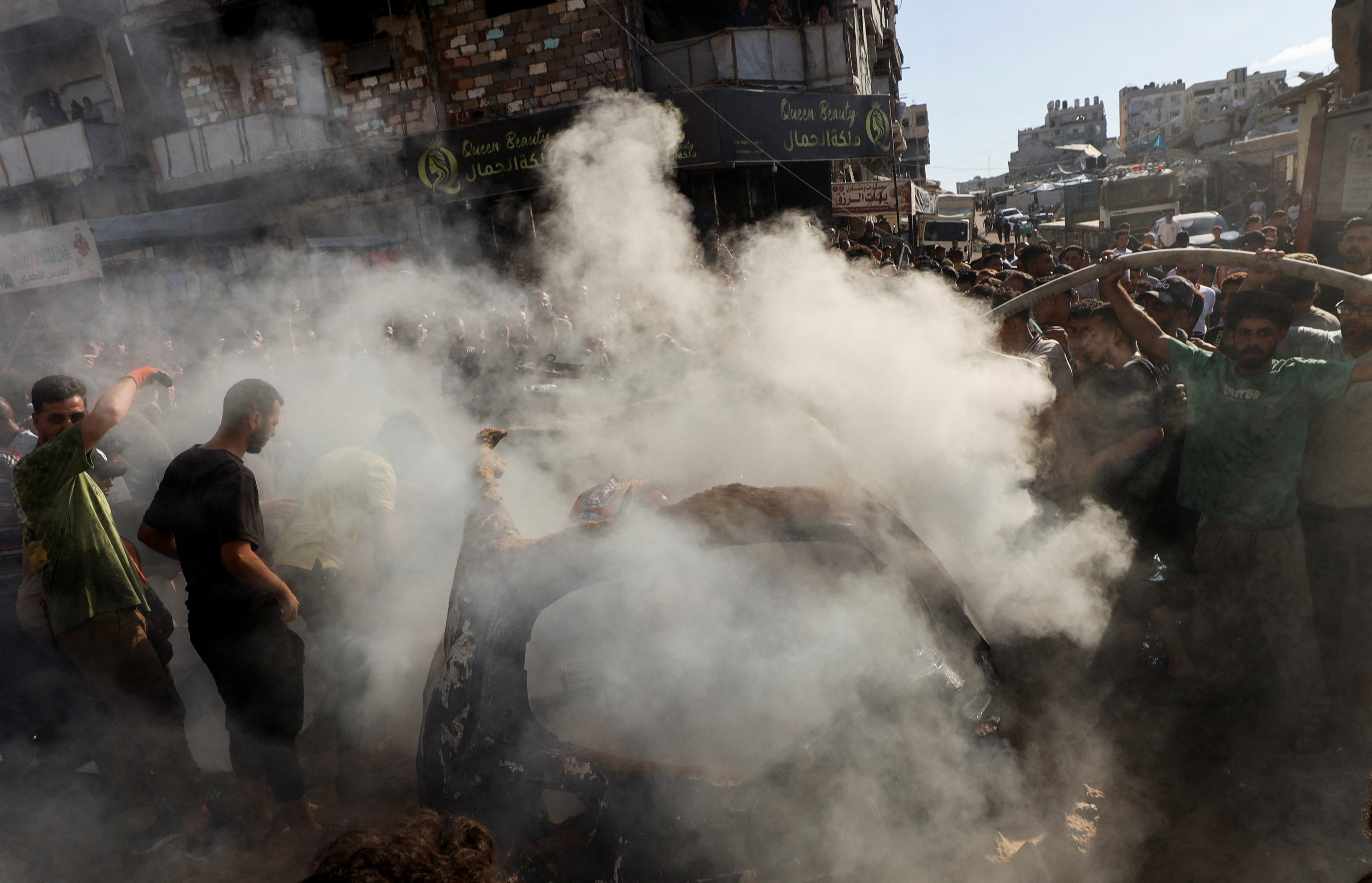 Palestinians inspect a vehicle hit by an Israeli air strike in Gaza City