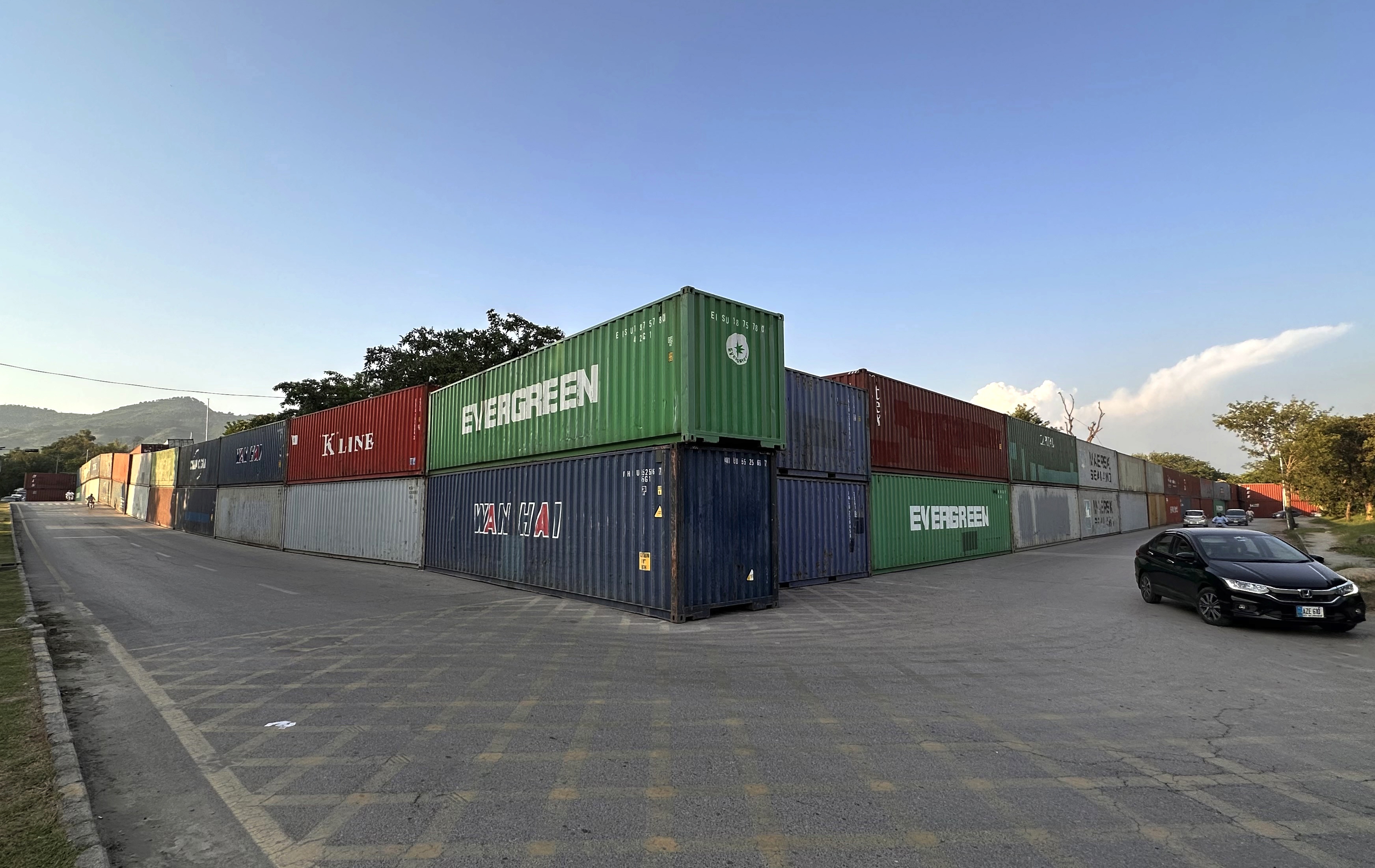 epa13248316 Commuters pass shipping containers lining Islamabads Red Zone, in Islamabad, Pakistan, 18 September 2026. Authorities have deployed containers and additional security personnel at key roads and entry points ahead of planned opposition protests and a Pakistan Tehreek-e-Insaf (PTI) long march scheduled for September 27, with the party demanding the release of former Prime Minister Khan. The security measures have disrupted traffic and raised concerns about restricted road access and the detention of commercial containers. EPA/SOHAIL SHAHZAD