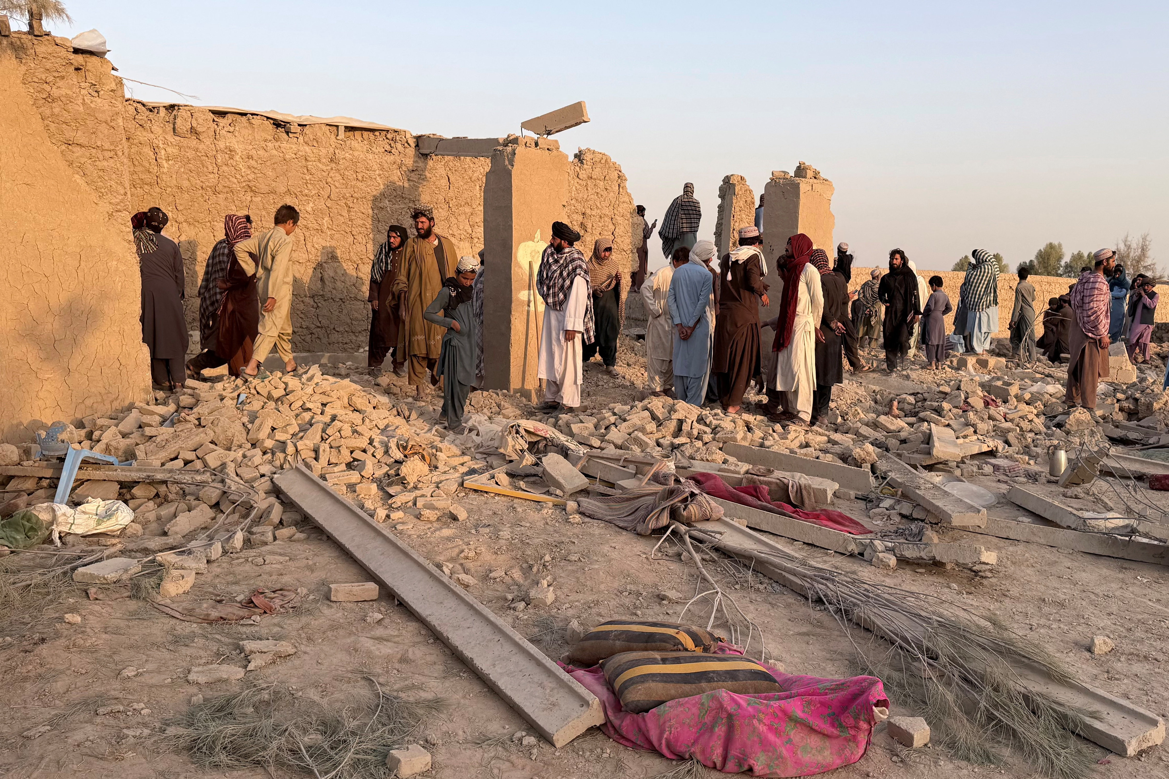People stand on the rubble of a house that was damaged in what the Taliban said was a Pakistani airstrike in Garmsir district in Helmand province