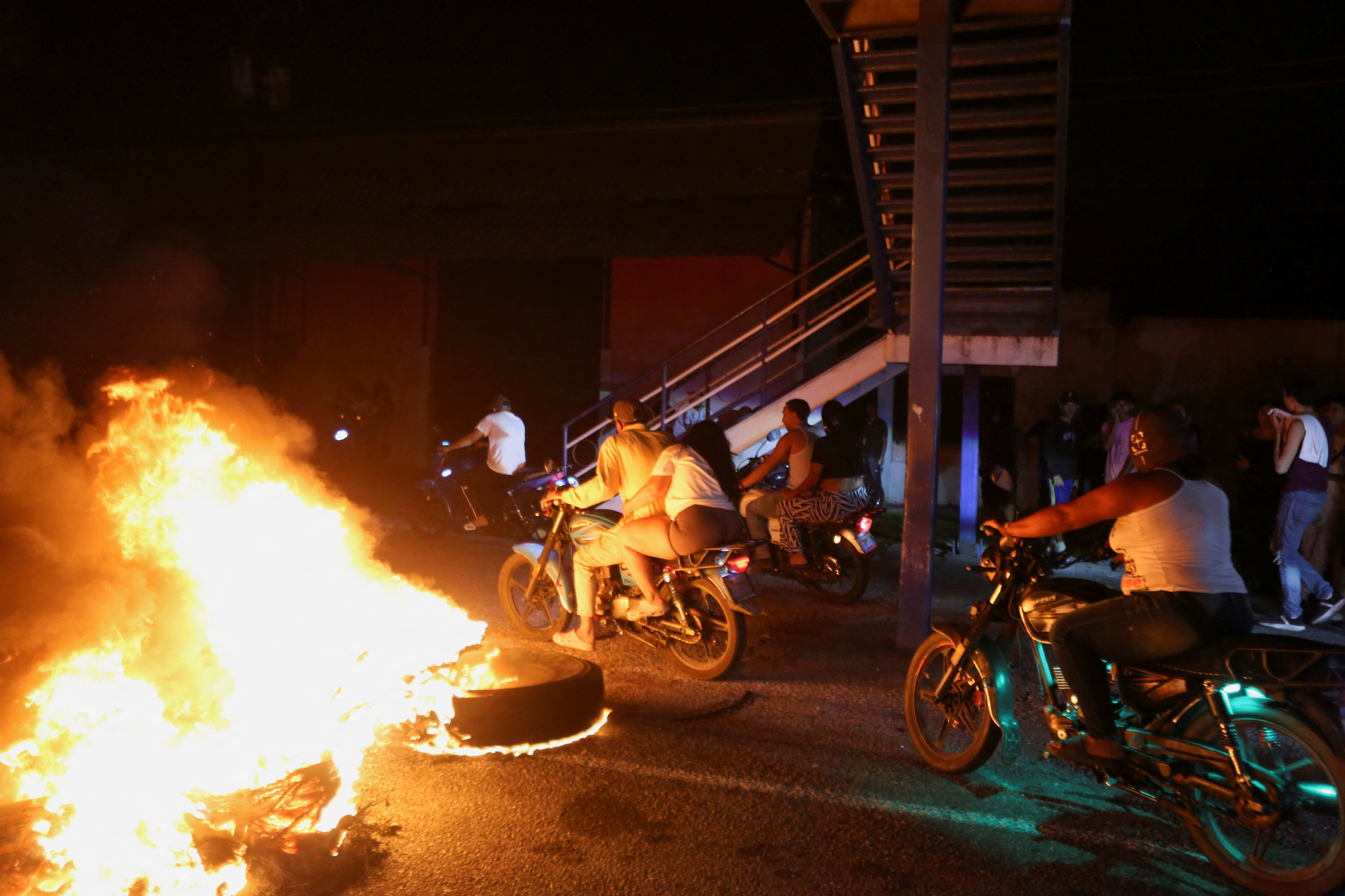 Motorcyclists pass by a burning roadblock during a protest over increasingly prolonged power outages in Guacara, Carabobo state, Venezuela, September 30, 2026. REUTERS/Juan Carlos Hernandez