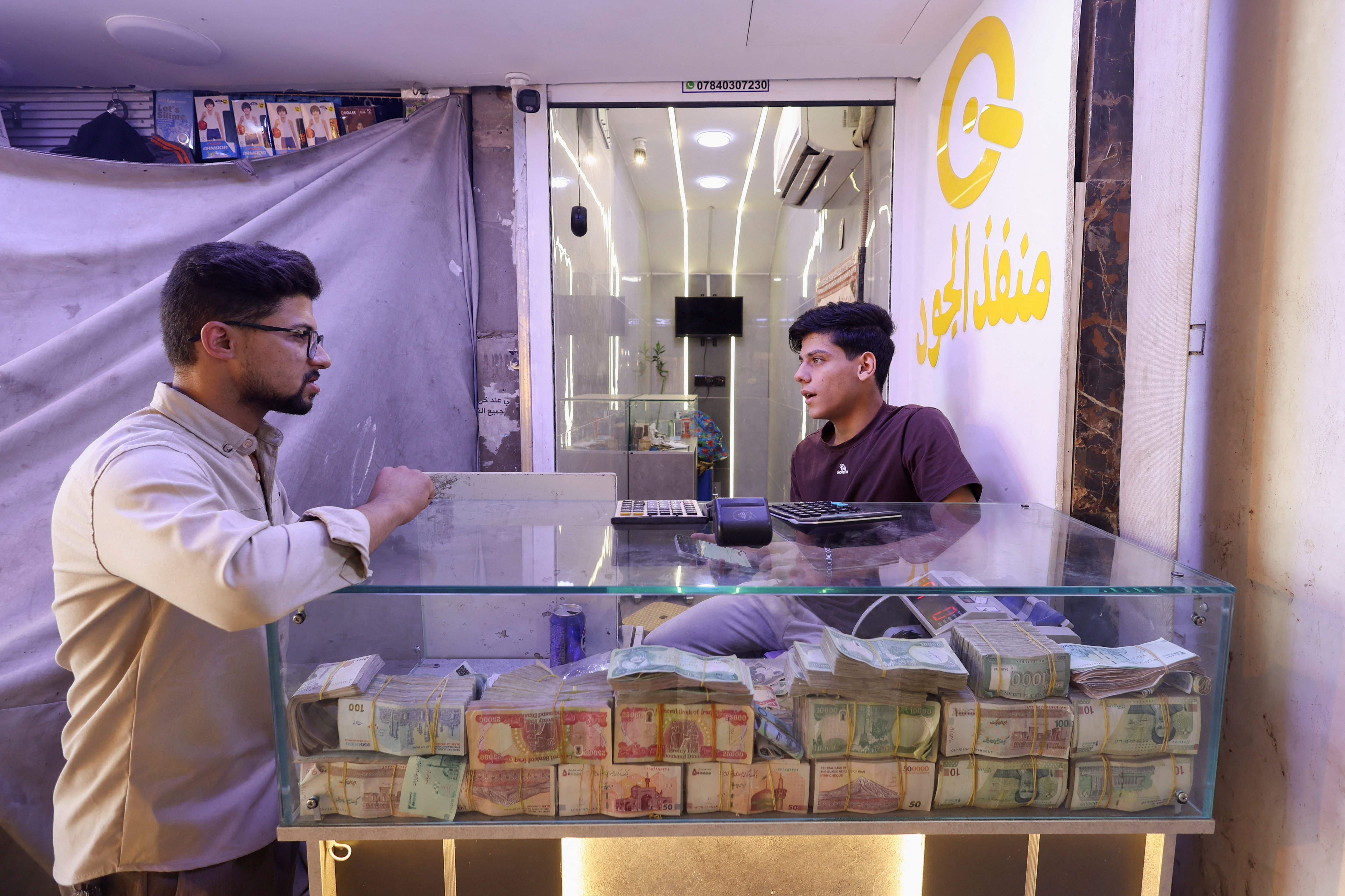 A customer visits a currency exchange shop in Najaf, Iraq, October 7, 2026. Iraq devalued its dinar to 1,520 per US dollar as disruptions to oil exports strained state revenues. REUTERS/Alaa Al-Marjani