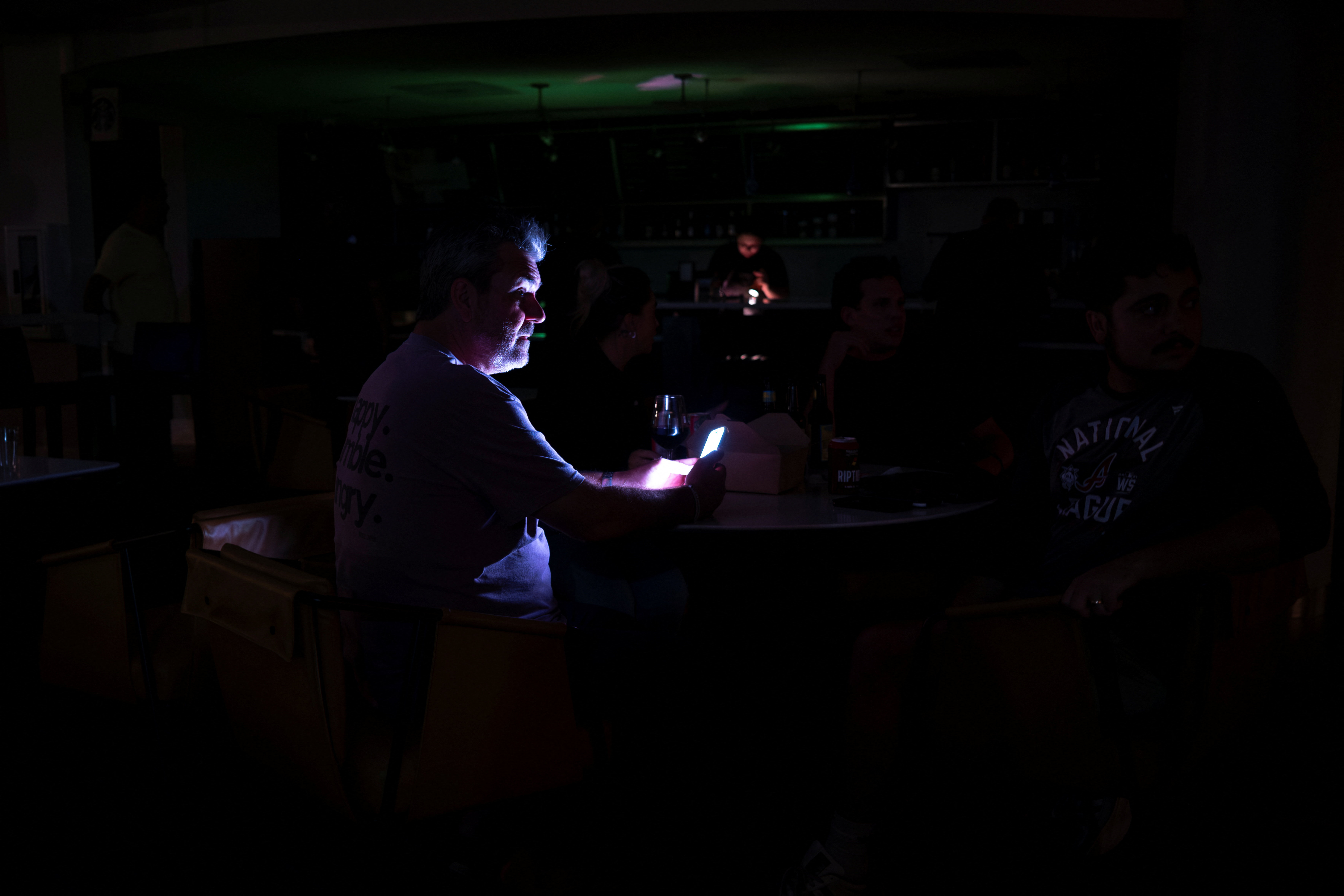 People relax in a hotel lobby during a power outage ahead of the arrival of Hurricane Isaias, in Pensacola, Florida, US, October 9, 2026. REUTERS/Marco Bello