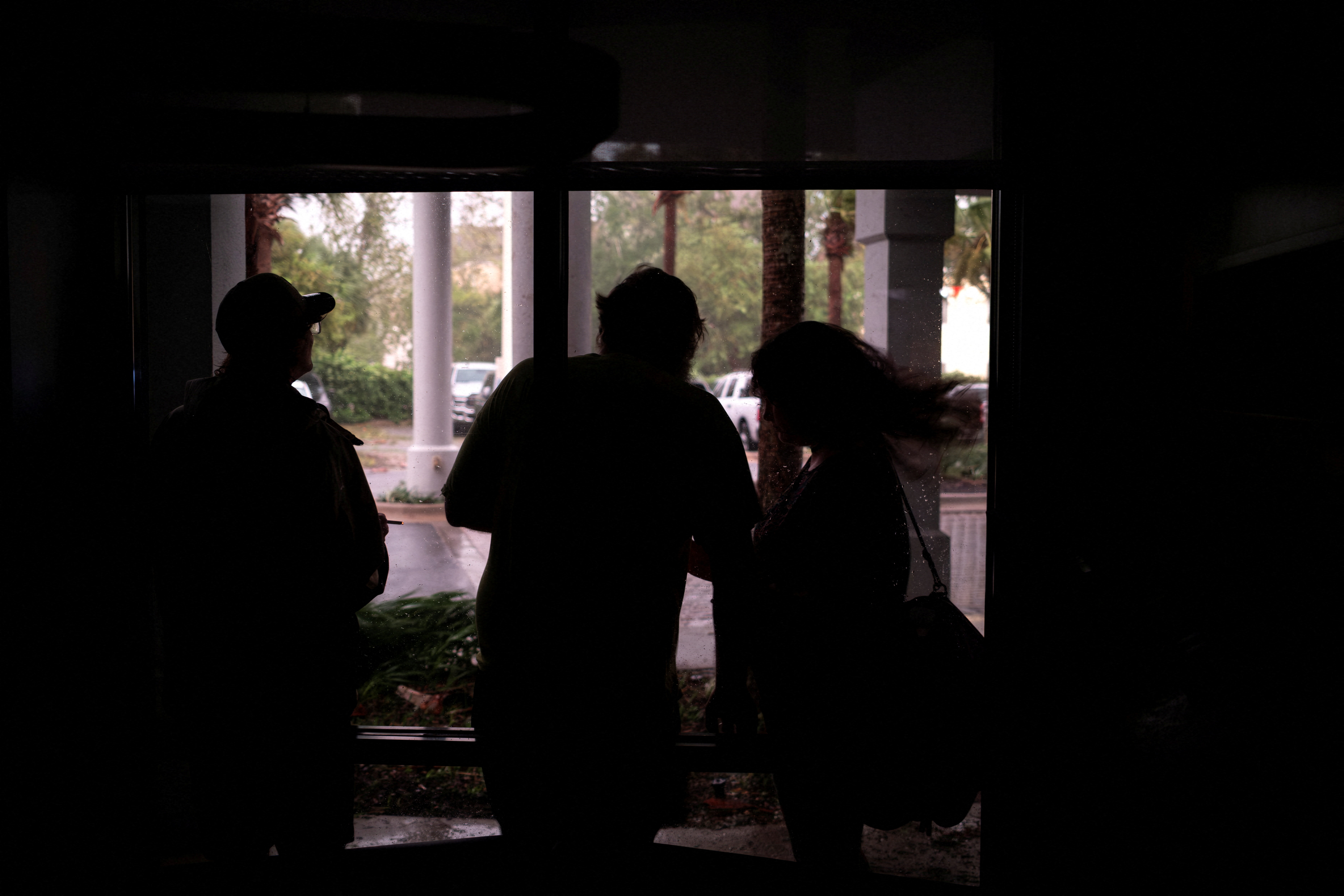 People look at wind, rain, and flying debris from a hotel lobby during a power outage ahead of the arrival of Hurricane Isaias, in Pensacola, Florida, US, October 9, 2026. REUTERS/Marco Bello