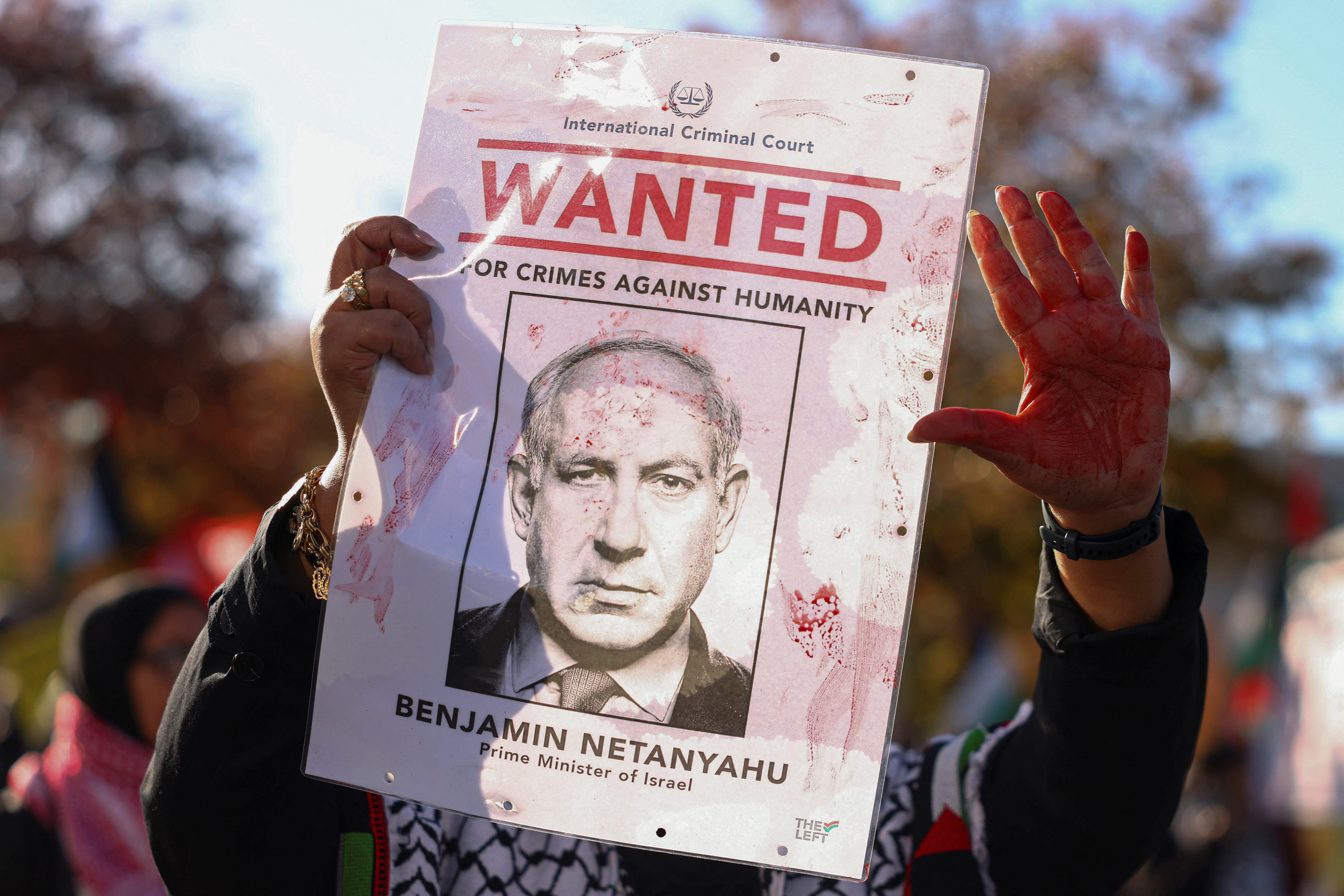 A protester holds a placard, depicting an arrest warrant for Israeli Prime Minister Benjamin Netanyahu, covered in fake blood during the "United for Palestine" demonstration in Berlin, Germany, October 10, 2026. REUTERS/Christian Mang