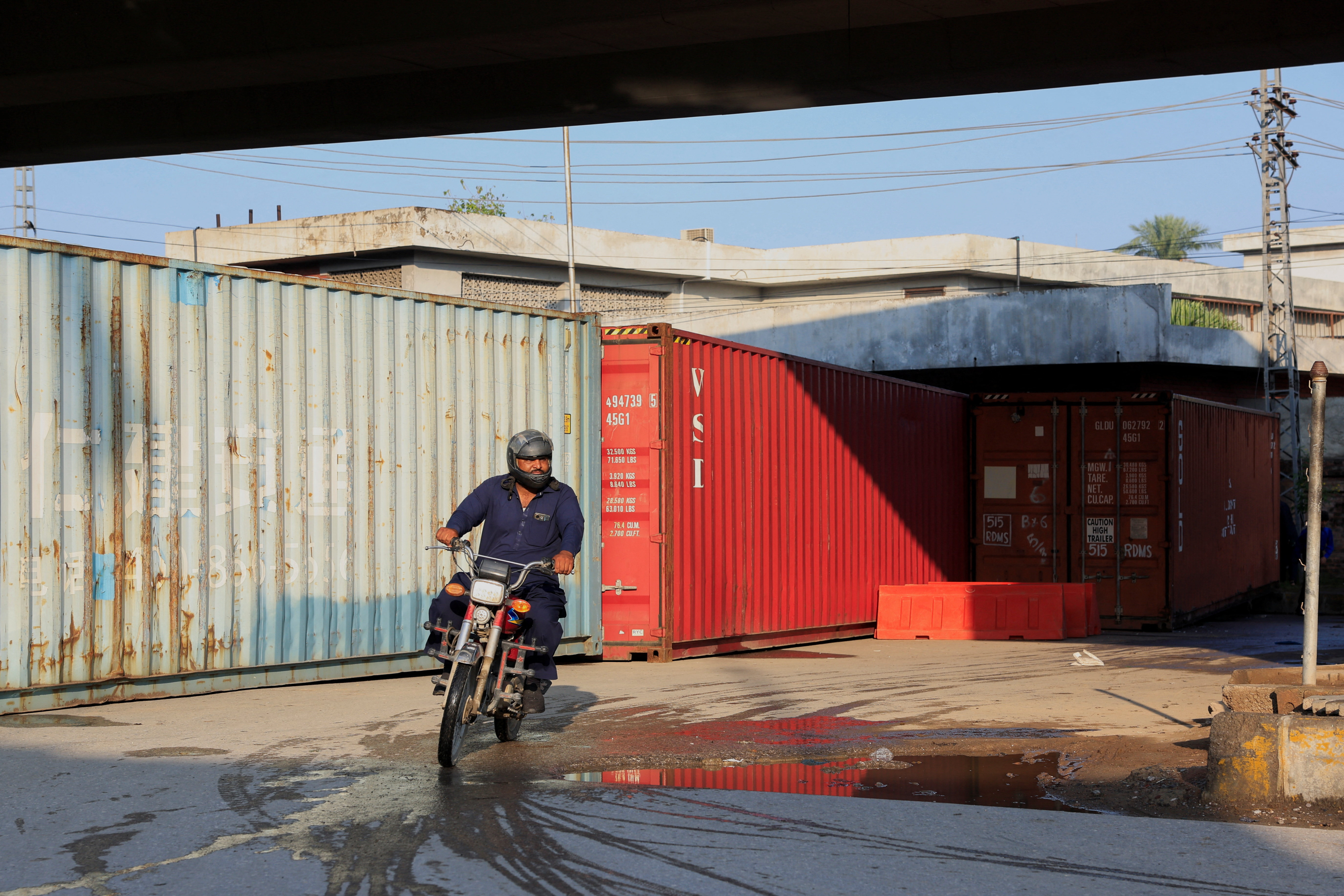 A man on motorbike rides past shipping containers used to block access to the Red Zone, a day after Pakistan imposed a state of emergency in Khyber Pakhtunkhwa province, effectively suspending the provincial government run by jailed former Prime Minister Imran Khan's party, in Peshawar, Pakistan, October 12, 2026. REUTERS