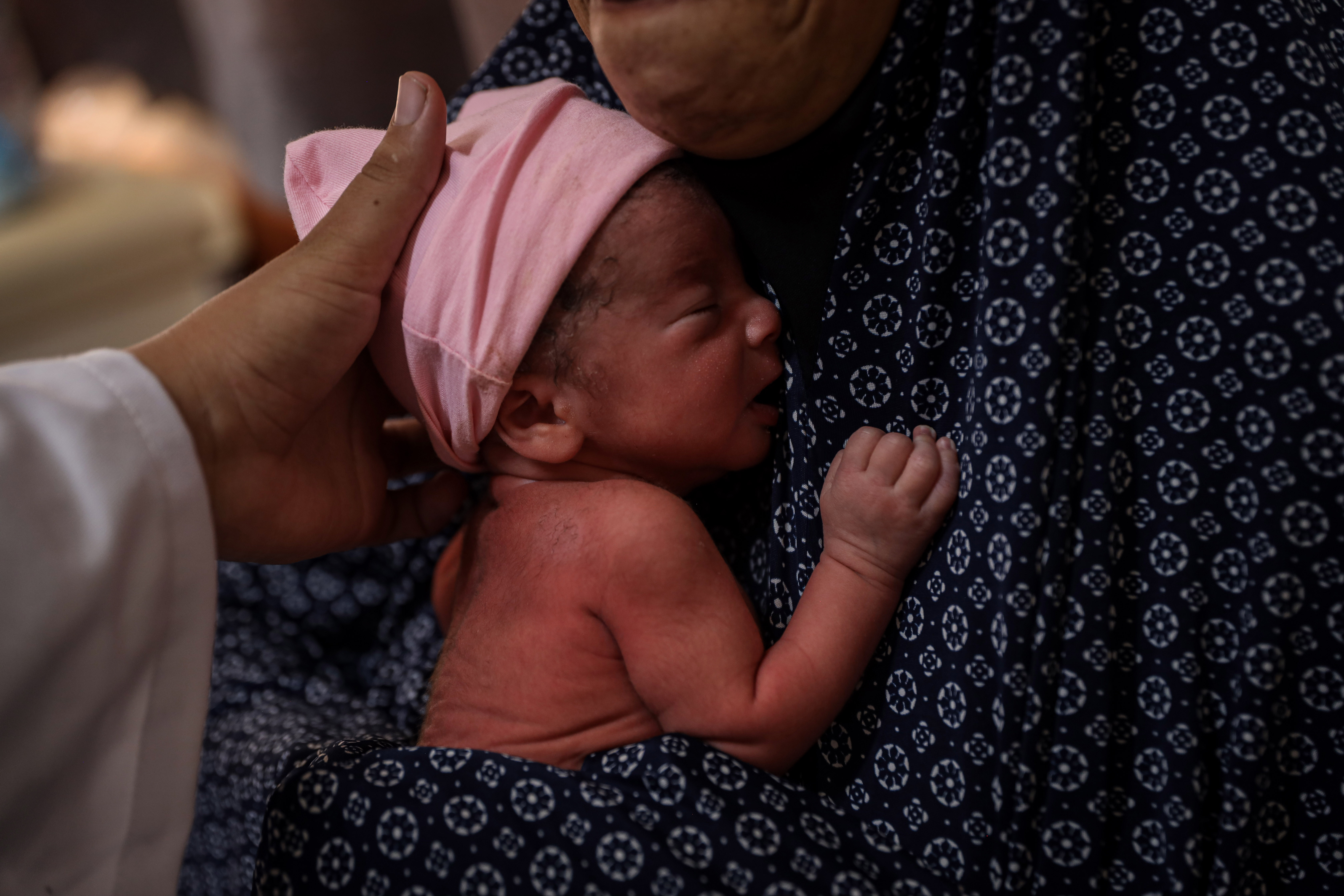 Linda Abu Nasira holds her newborn daughter during a kangaroo care session. [Abdelhakim Abu Riash/ Al Jazeera]