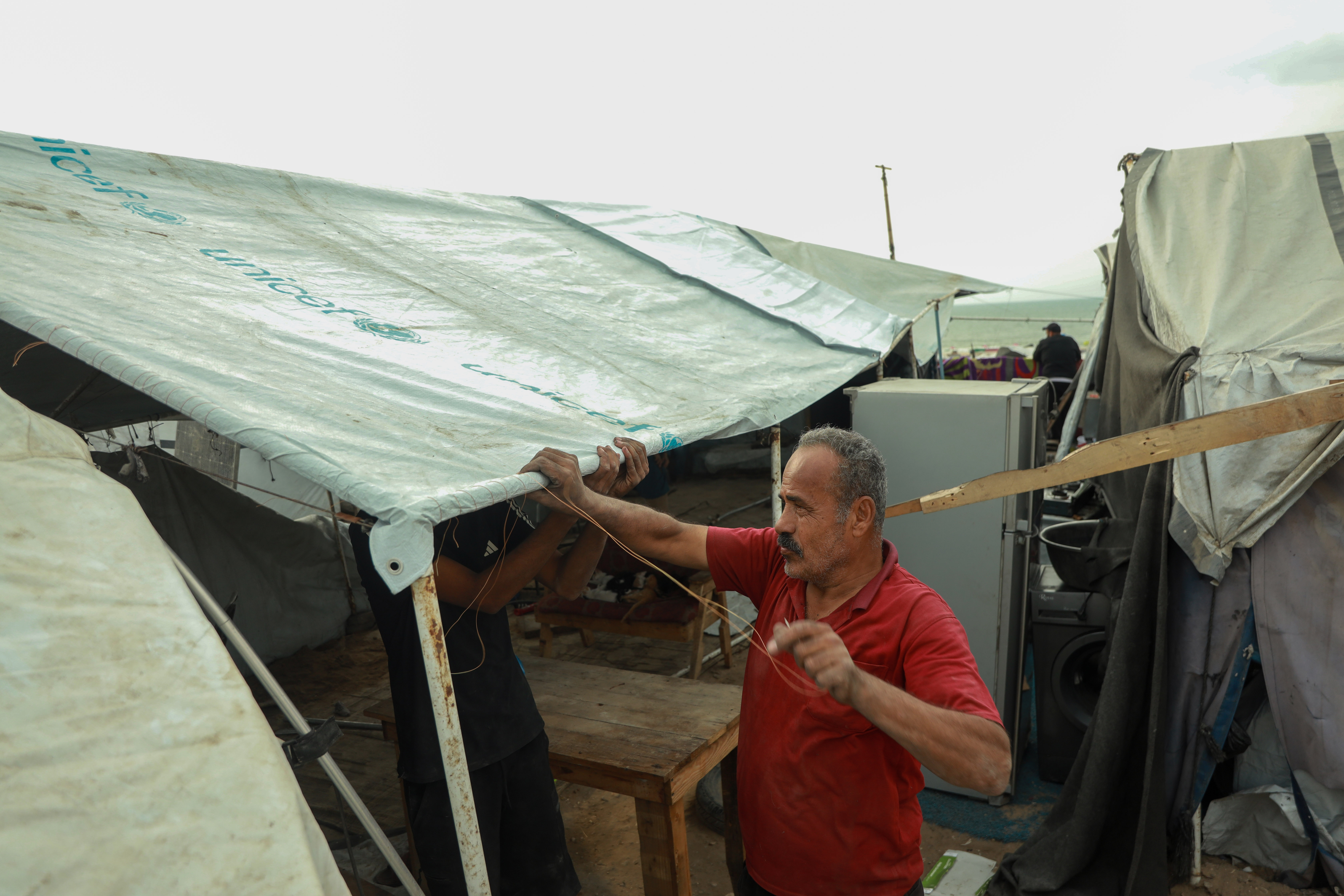 Mohammed al-Jamal tries to secure his family’s worn-out tent in advance of Gaza’s fourth winter of displacement