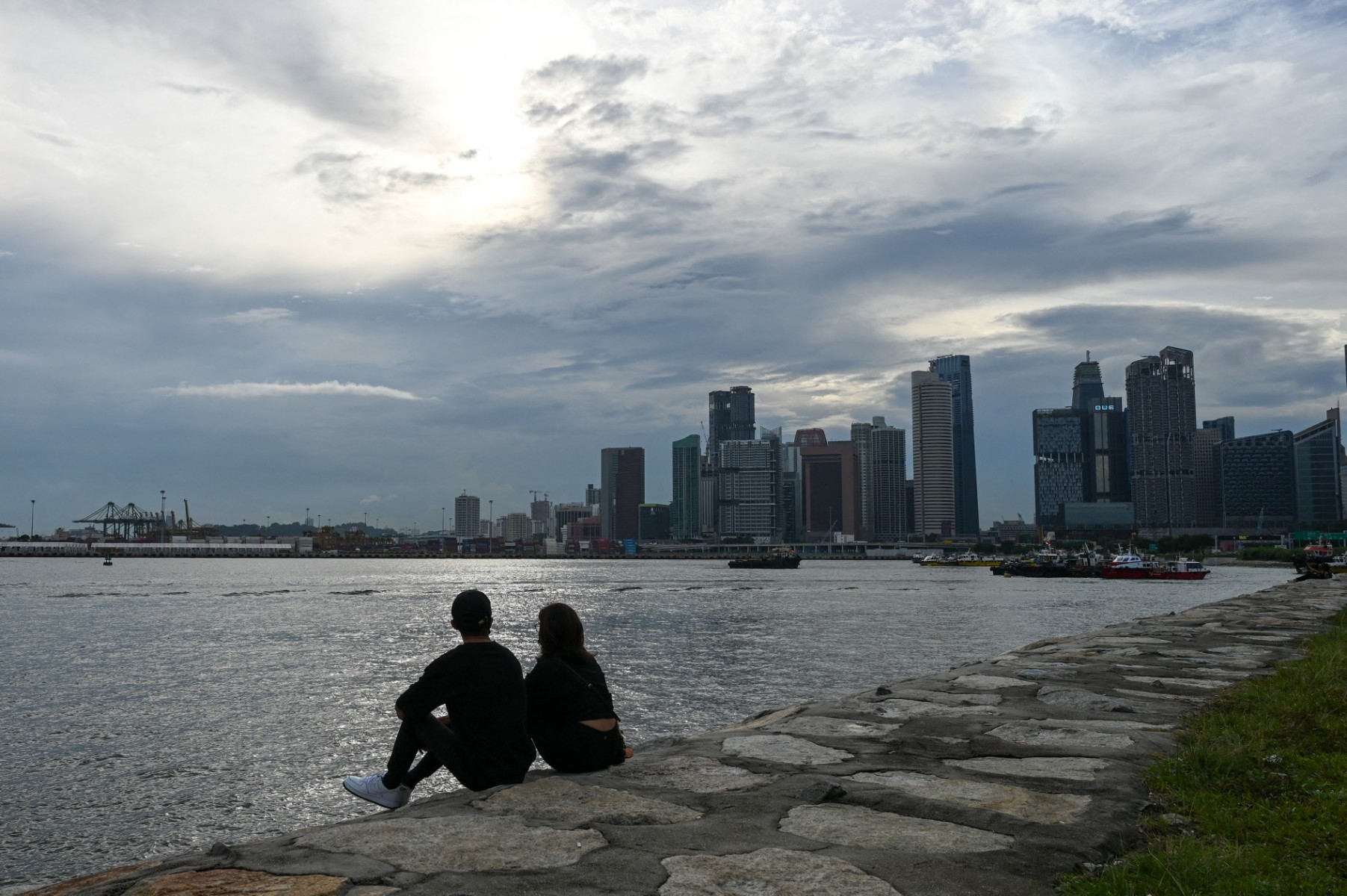 A couple sits along the breakwater rocks in Singapore on August 13, 2021
