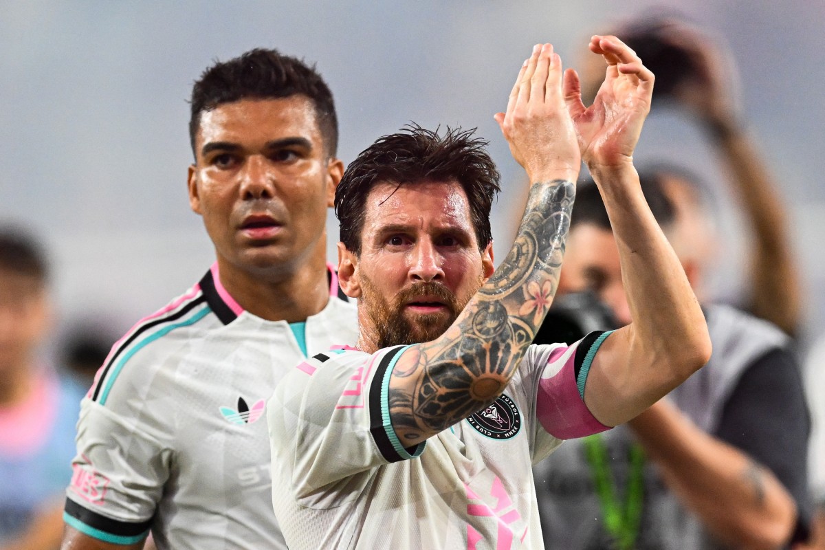 Inter Miami's Argentinian forward #10 Lionel Messi, flanked by Brazilian defender #05 Casemiro, applauds towards his fans.