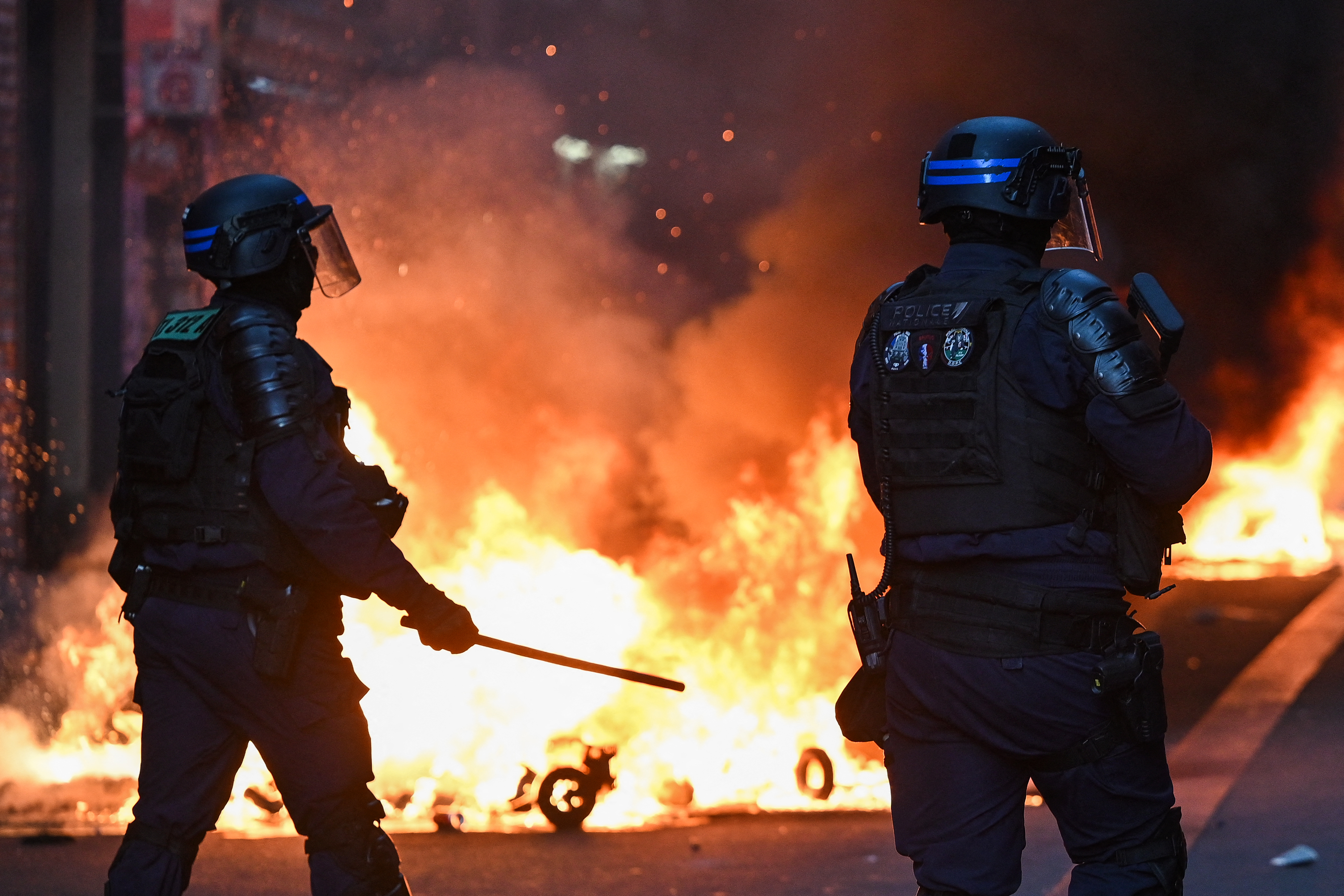 Police officers stand in front of a fire