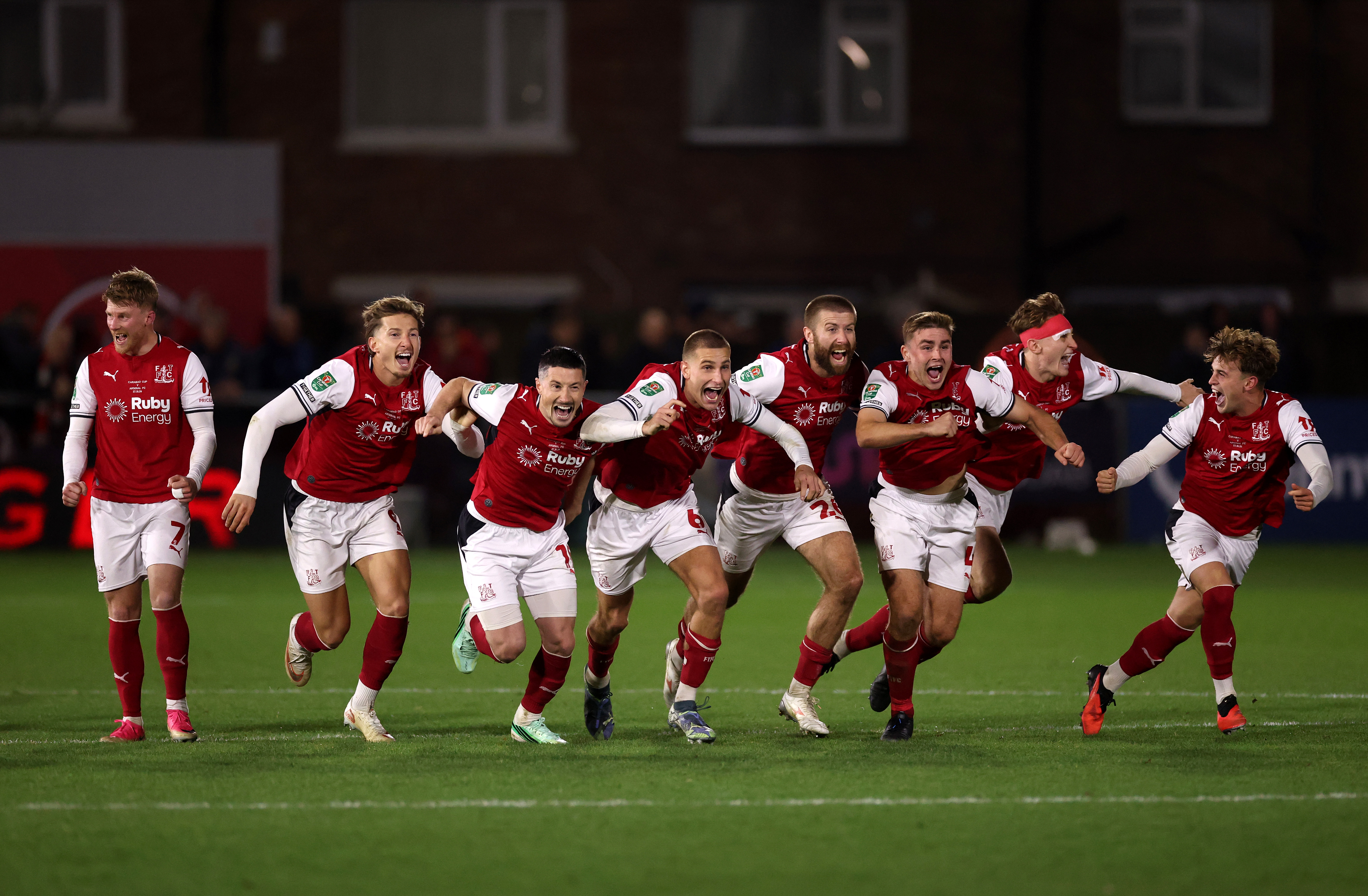 FLEETWOOD, ENGLAND - OCTOBER 27: Fleetwood Town players celebrate after Jay Lynch of Fleetwood Town saves a penalty from Bruno Guimaraes of Arsenal to win the match during the Carabao Cup Fourth Round match between Fleetwood Town and Arsenal at Highbury Stadium on October 27, 2026 in Fleetwood, England. (Photo by Carl Recine/Getty Images)