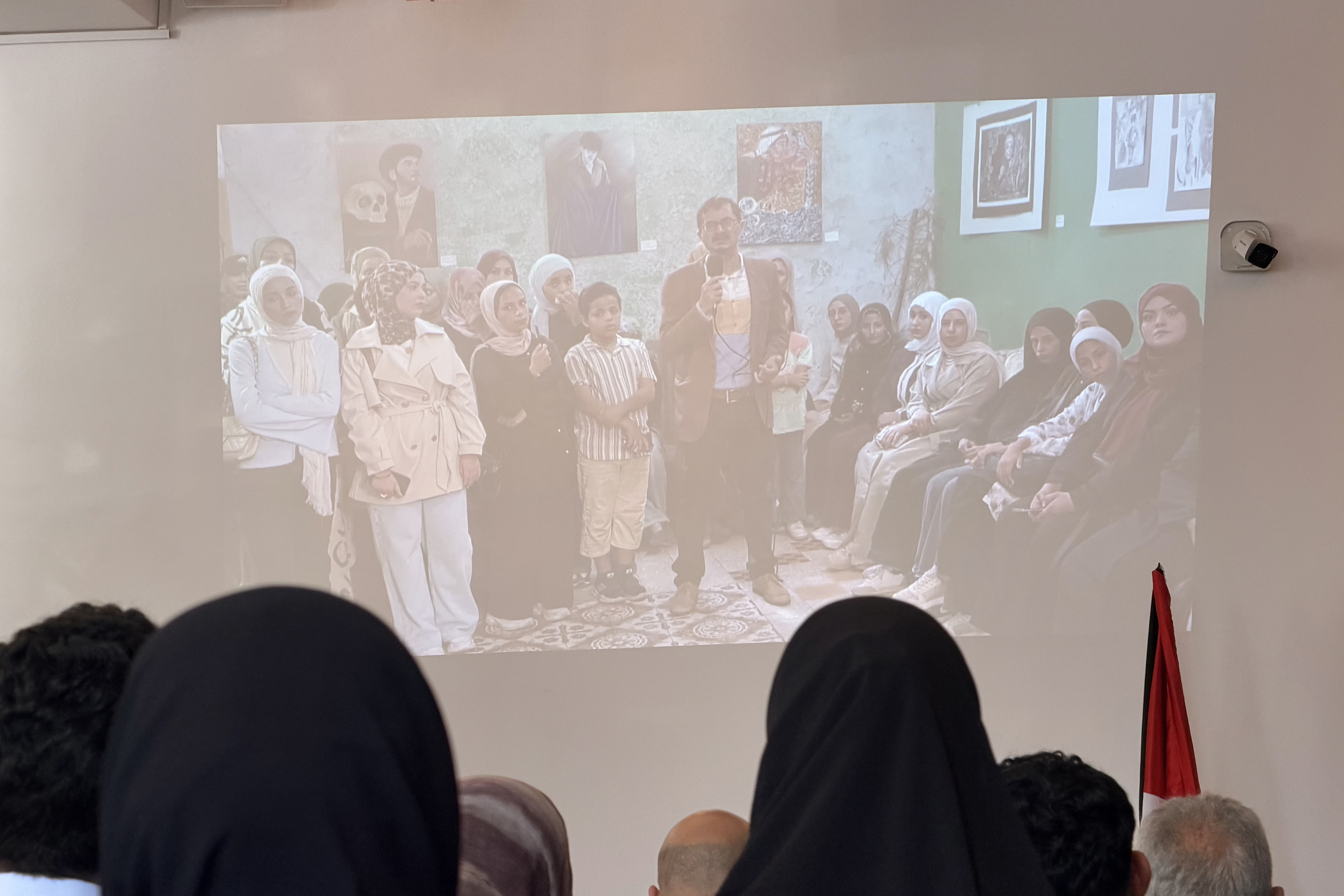 Painter and juror Ghanem Al Den, speaking from his studio in Bureij refugee camp in central Gaza, addresses visitors at the Bethlehem Peace Center by live feed at the opening of the Anamel Falasteen exhibition on October 13, 2026