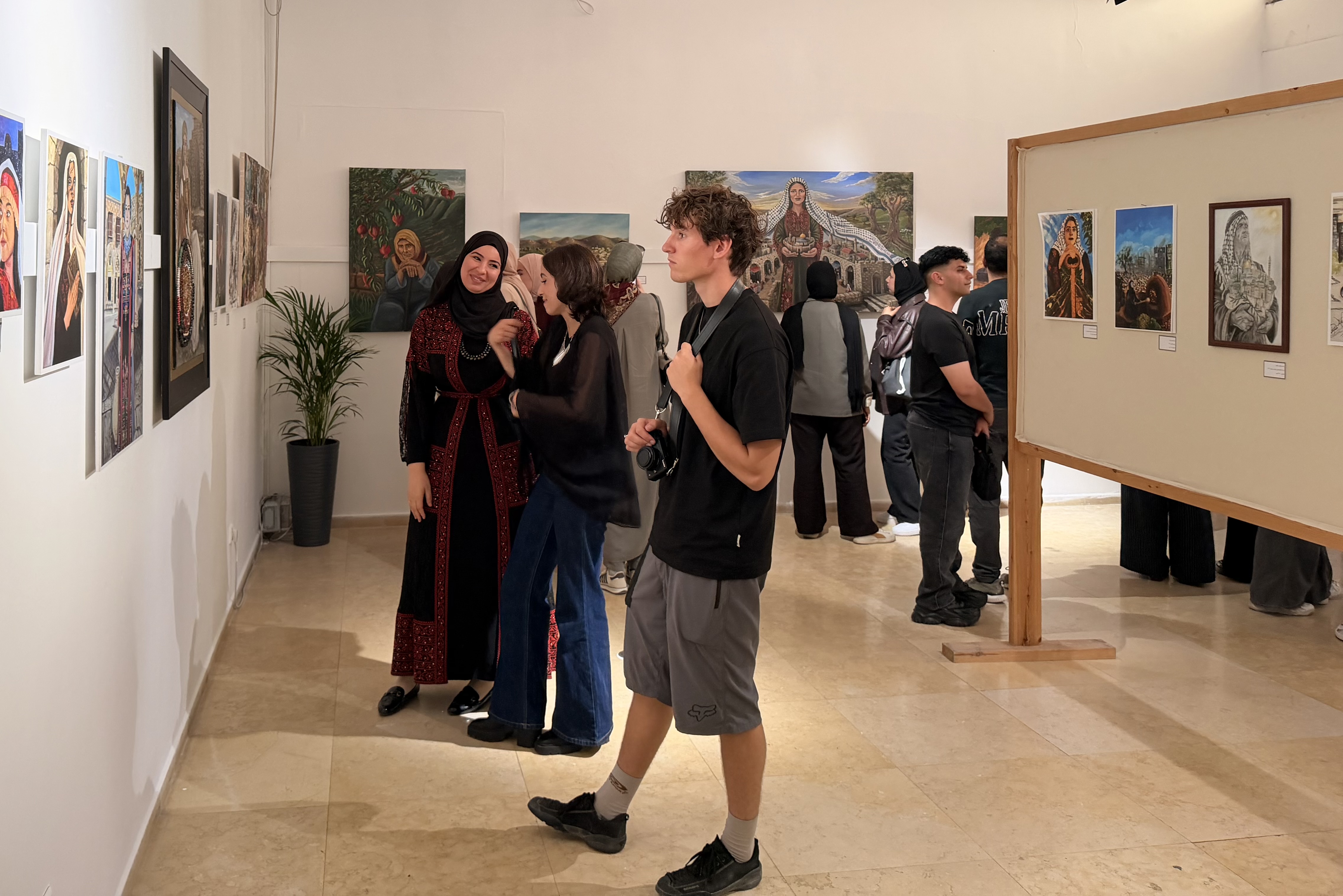 Visitors look at works by young Palestinian artists from Gaza and the occupied West Bank at the opening of the Anamel Falasteen exhibition at the Bethlehem Peace Center on October 13, 2026