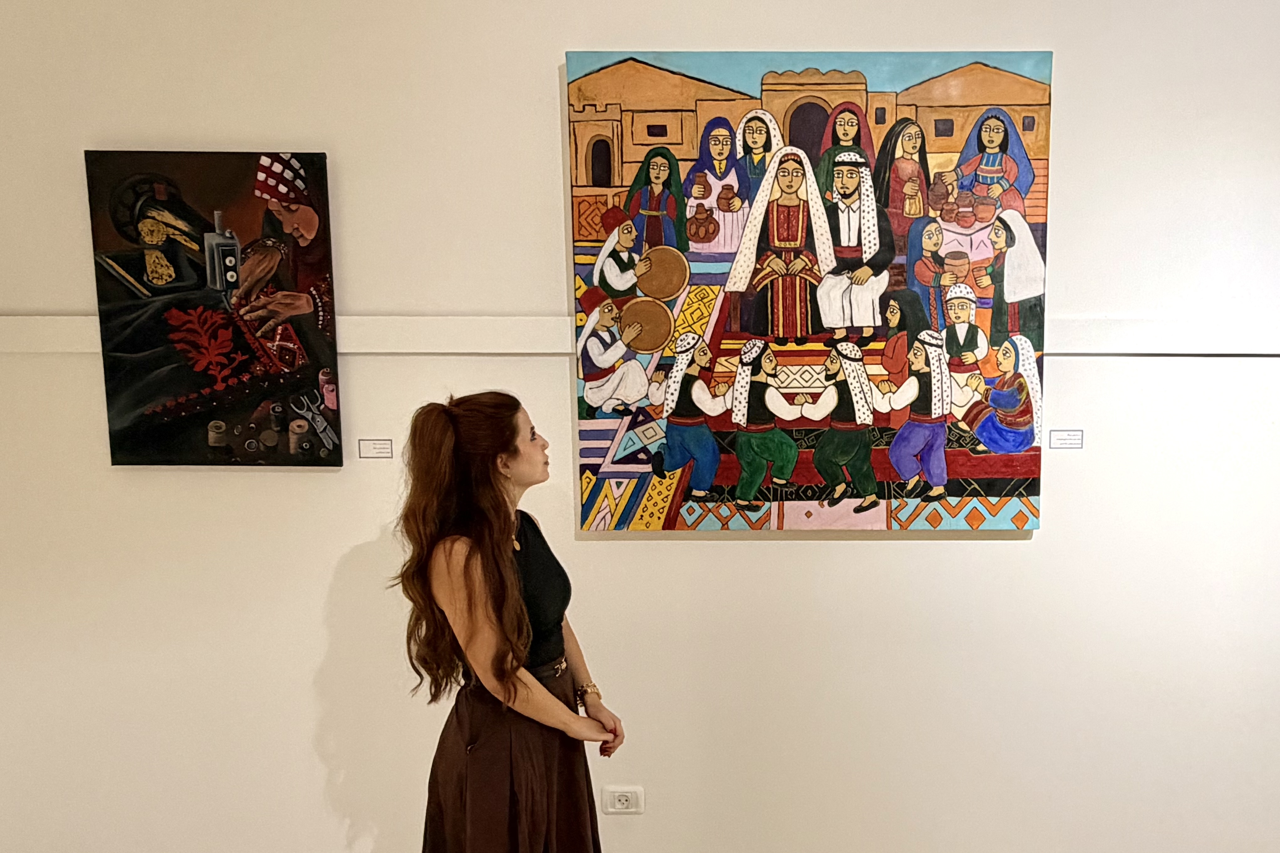 Hanan Barghouthi, 24, a visual artist from Ramallah, looks at her painting of a Palestinian wedding on display at the Anamel Falasteen exhibition at the Bethlehem Peace Center on October 13, 2026